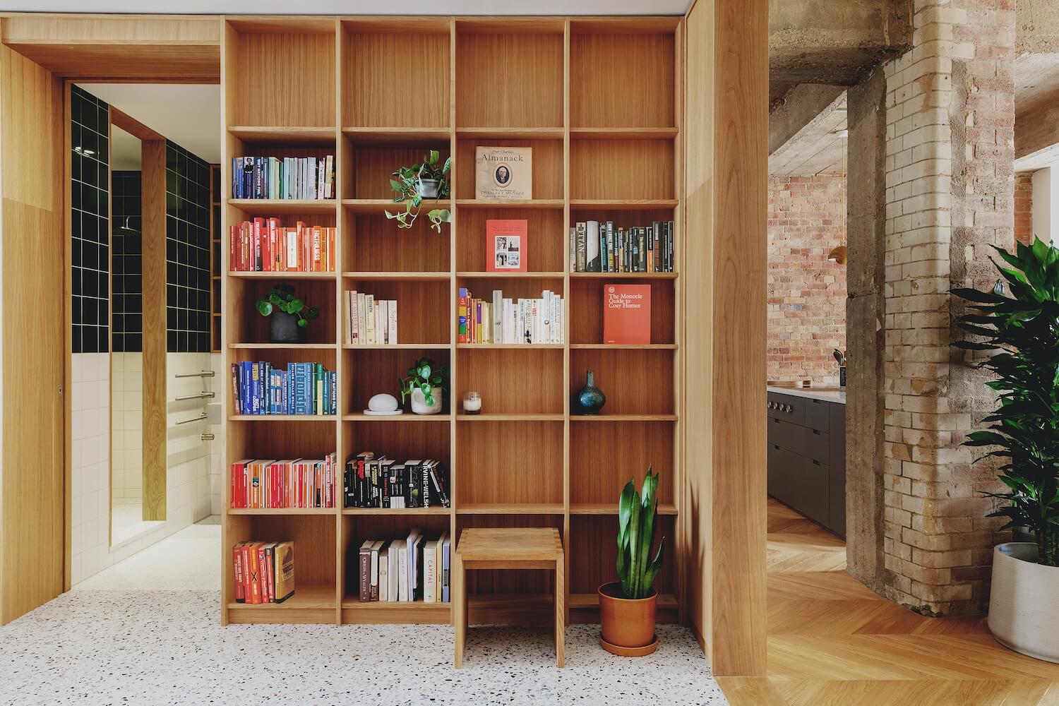 A residential interior made of wood, including a wall to ceiling bookshelf