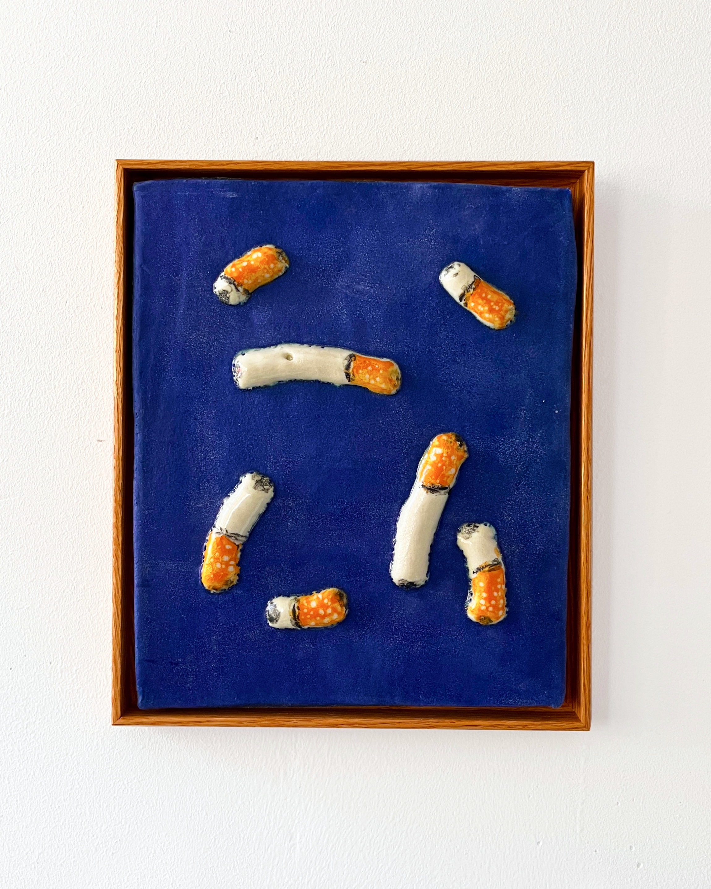 Cigarettes 1, 2025, ceramic glaze on stoneware, oak frame, 16"x12"