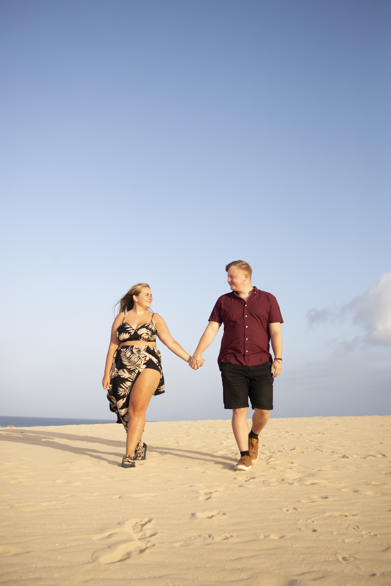 Couple walking hand in hand along Fuerteventura dunes at sunset