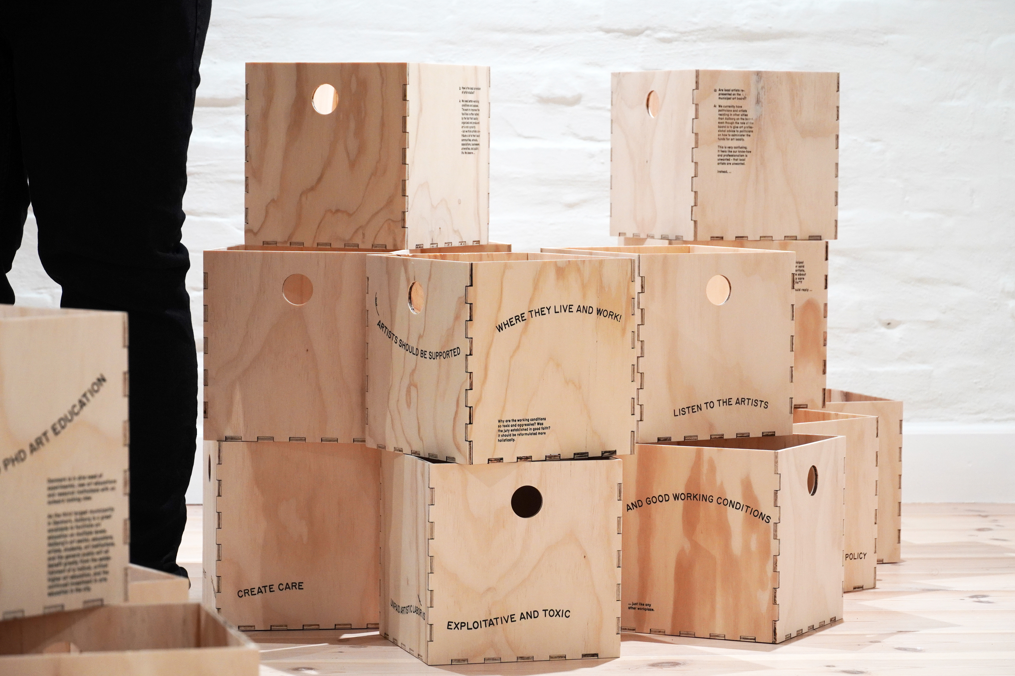 Wooden storage boxes with statements calling for policy changes within the local visual art scene in Aalborg,  The Department of CCCC (Culture, Care, Commoning, and Critique), Aalborg Artist’s Association (AAAA), lím collective, Aalborg, 2022