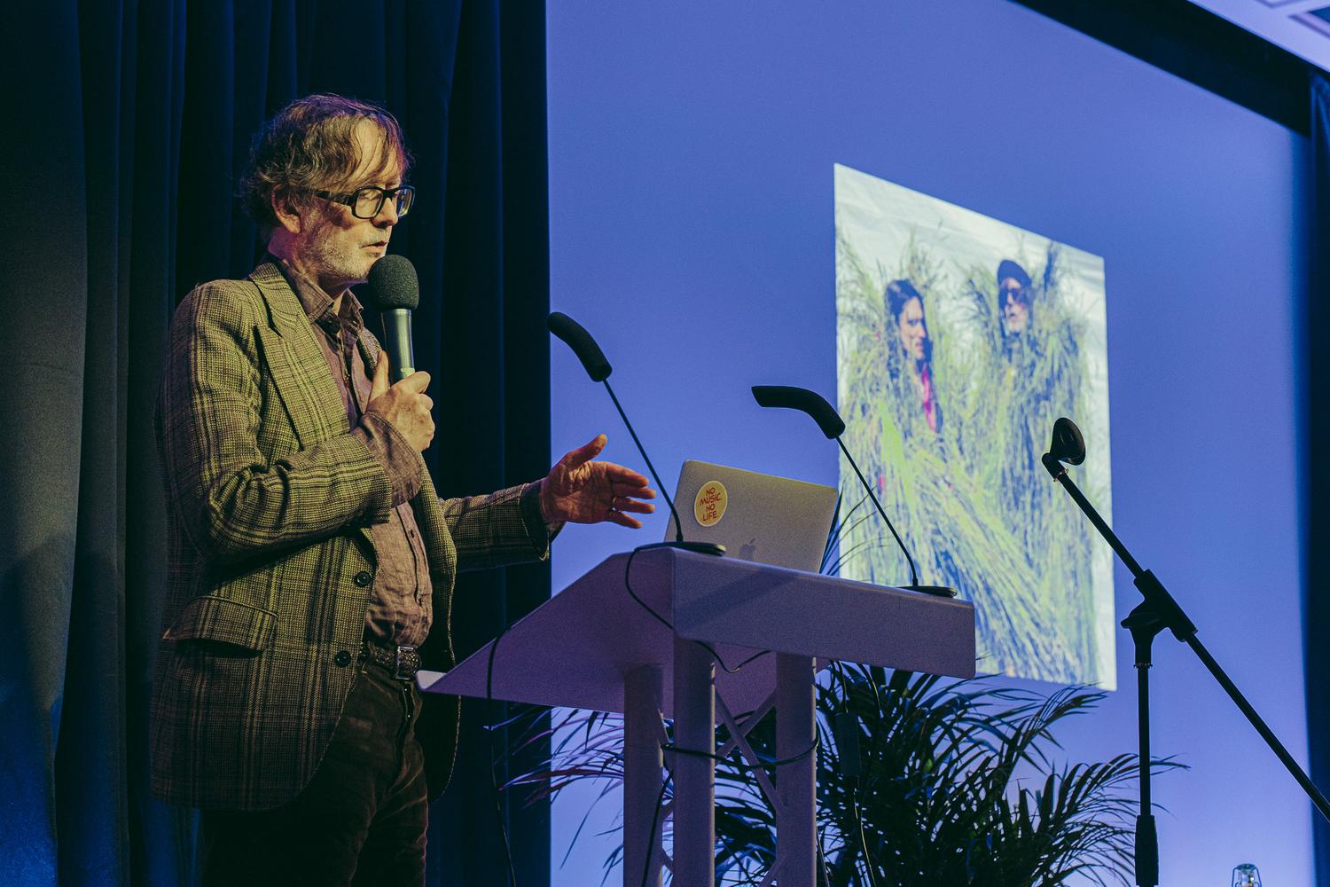 Jarvis Cocker speaking at AVA London with an image projected behind him.