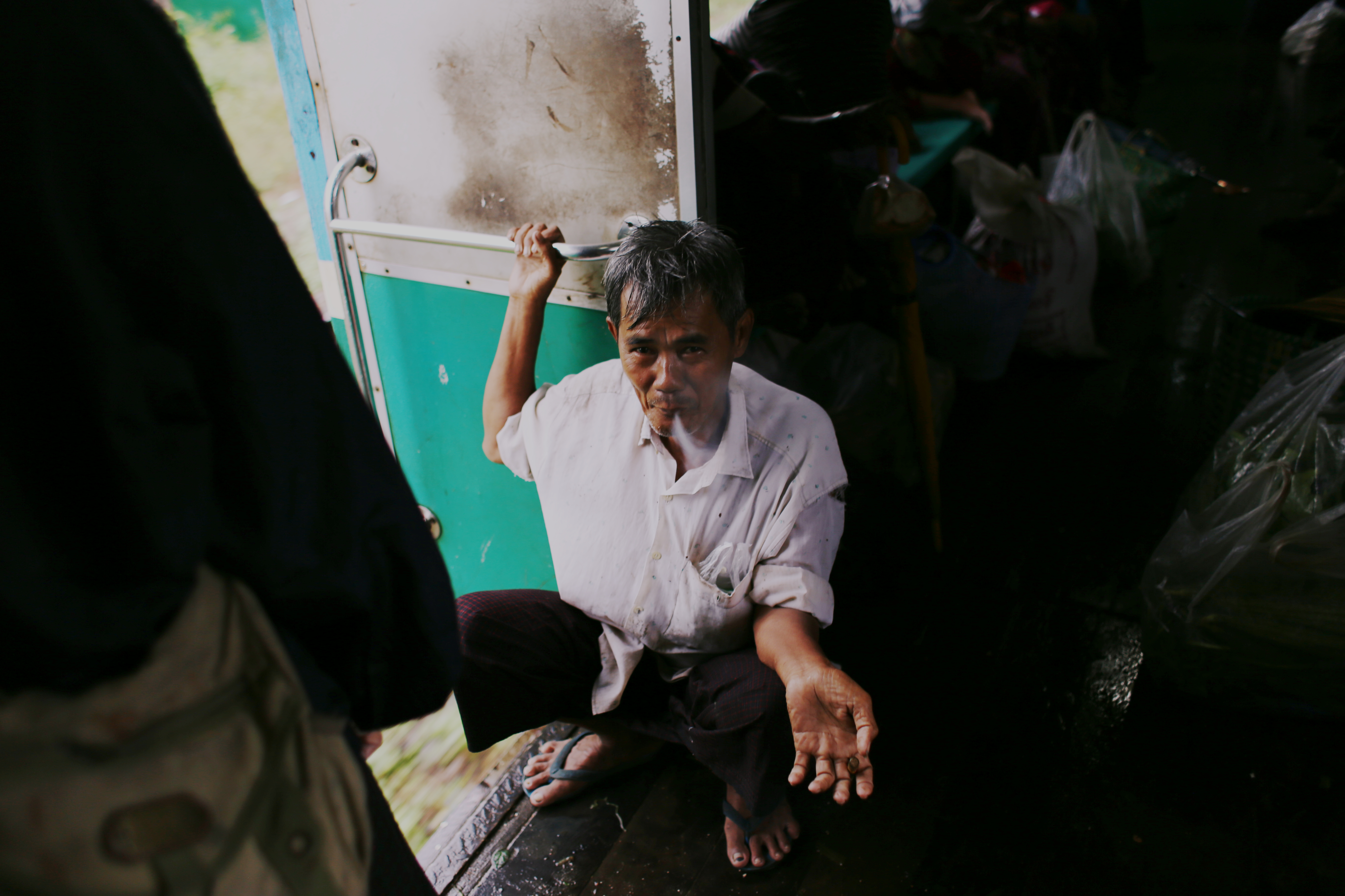 A trader enjoys a well-earned break before once again hauling his bags out of the carriage and onto the next platform. He smokes a cheroot, a traditional Burmese cigar, popular and cheap.