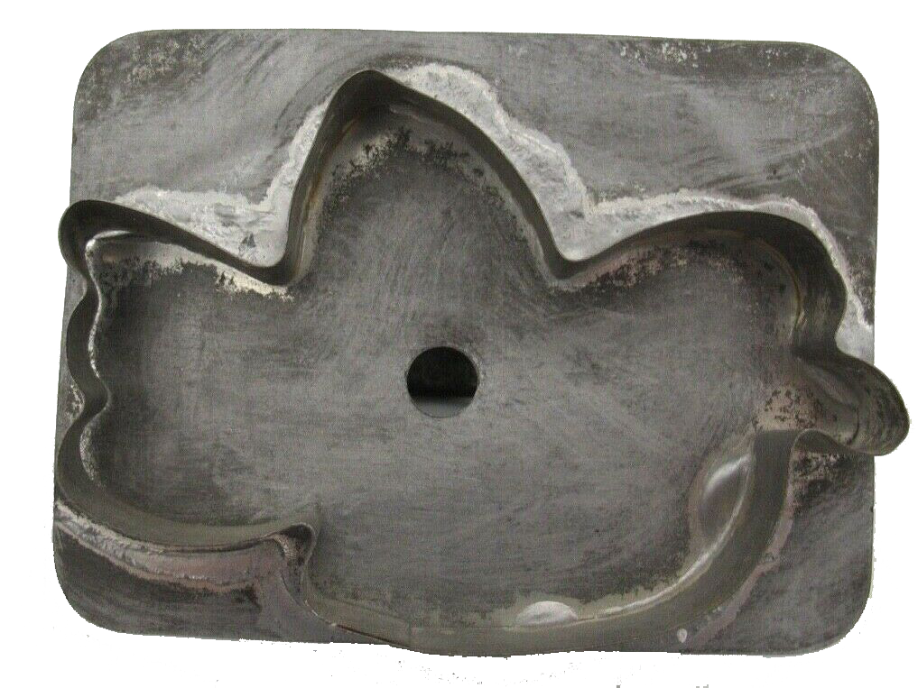 A vintage tin cookie cutter in the shape of a bird in flight.