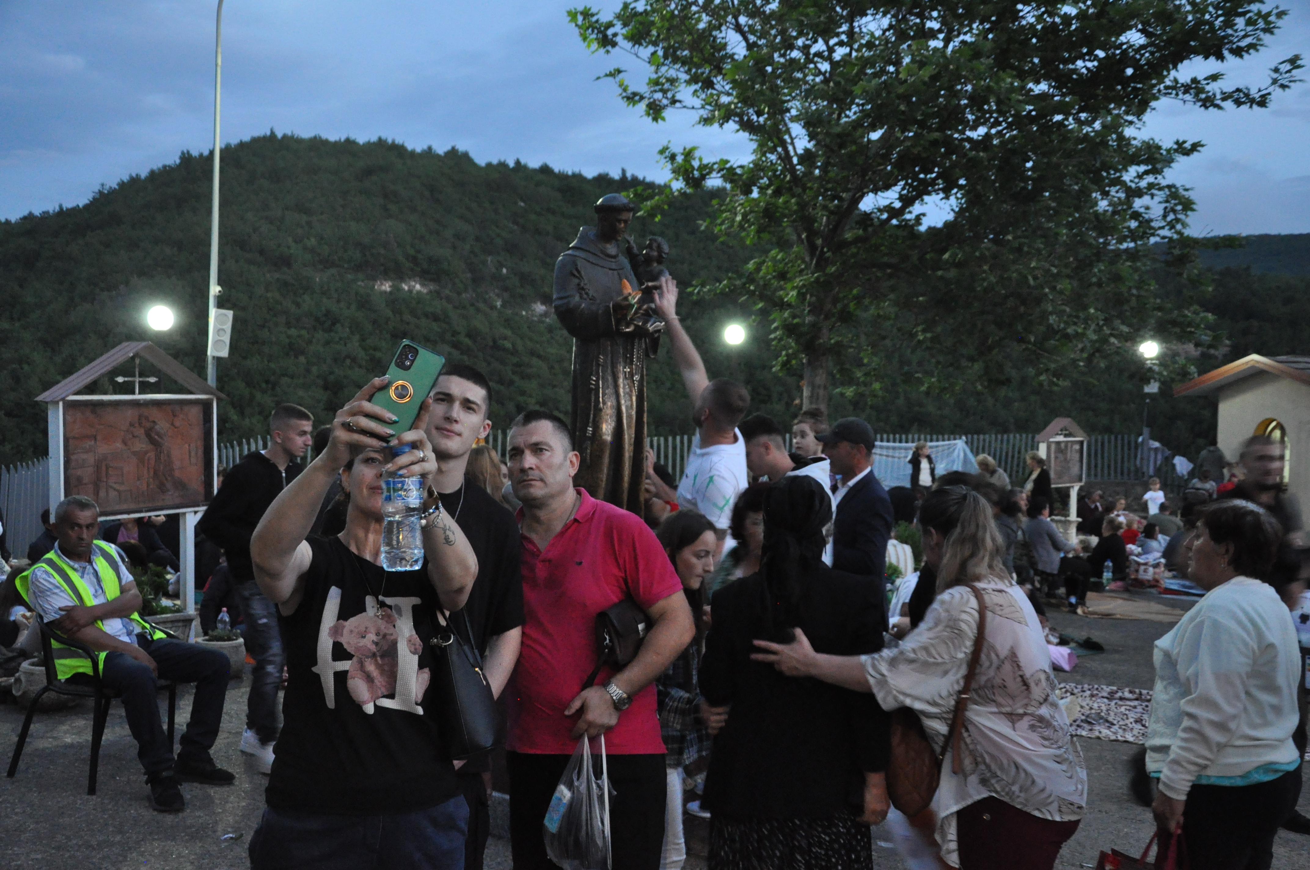 Group of pilgrims, probably a family, taking a snapshot selfie in front of the Statue of St. Anthony. 
