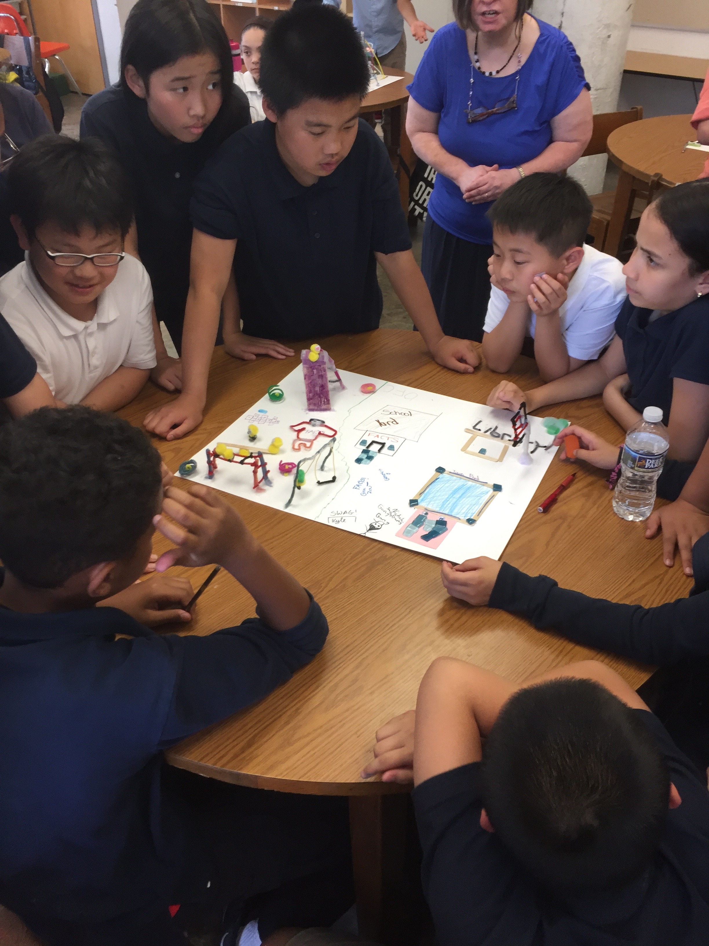  Photo shows a group of students at Folk Arts Cultural Treasures Charter School in Chinatown North Philadelphia leaning over a model they built that showcases their ideas for neighborhood development