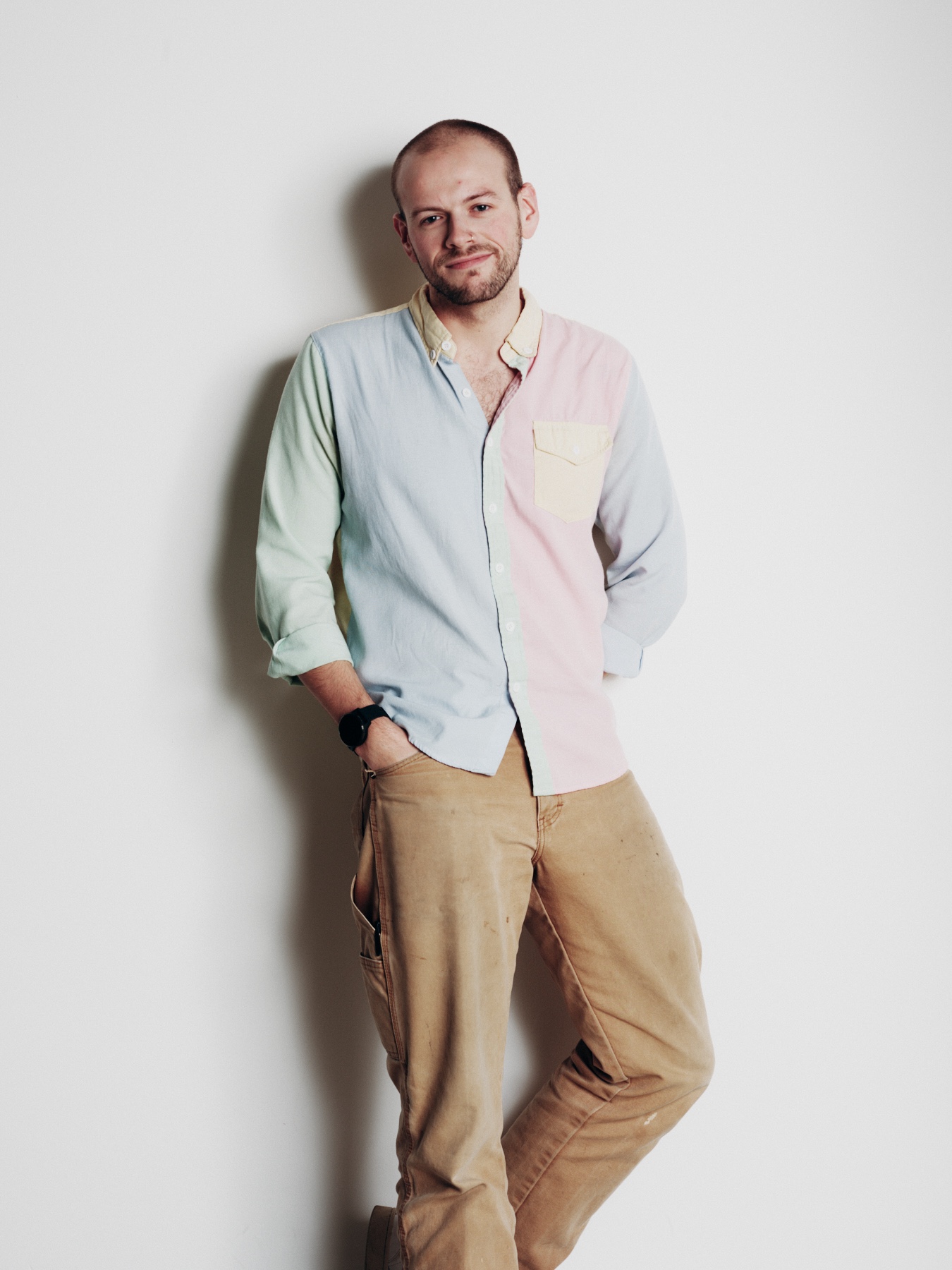 Ciaran, Marketing & Events Producer at UP! Productions, wearing a pastel colour-block shirt and tan trousers against a white background.