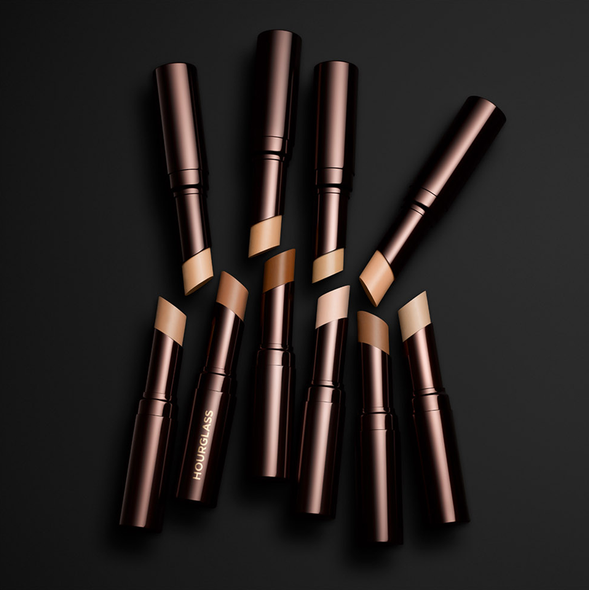 KMA stylist Rachel Haas designs set for photo of many shades of concealer sticks on black background for Hourglass 