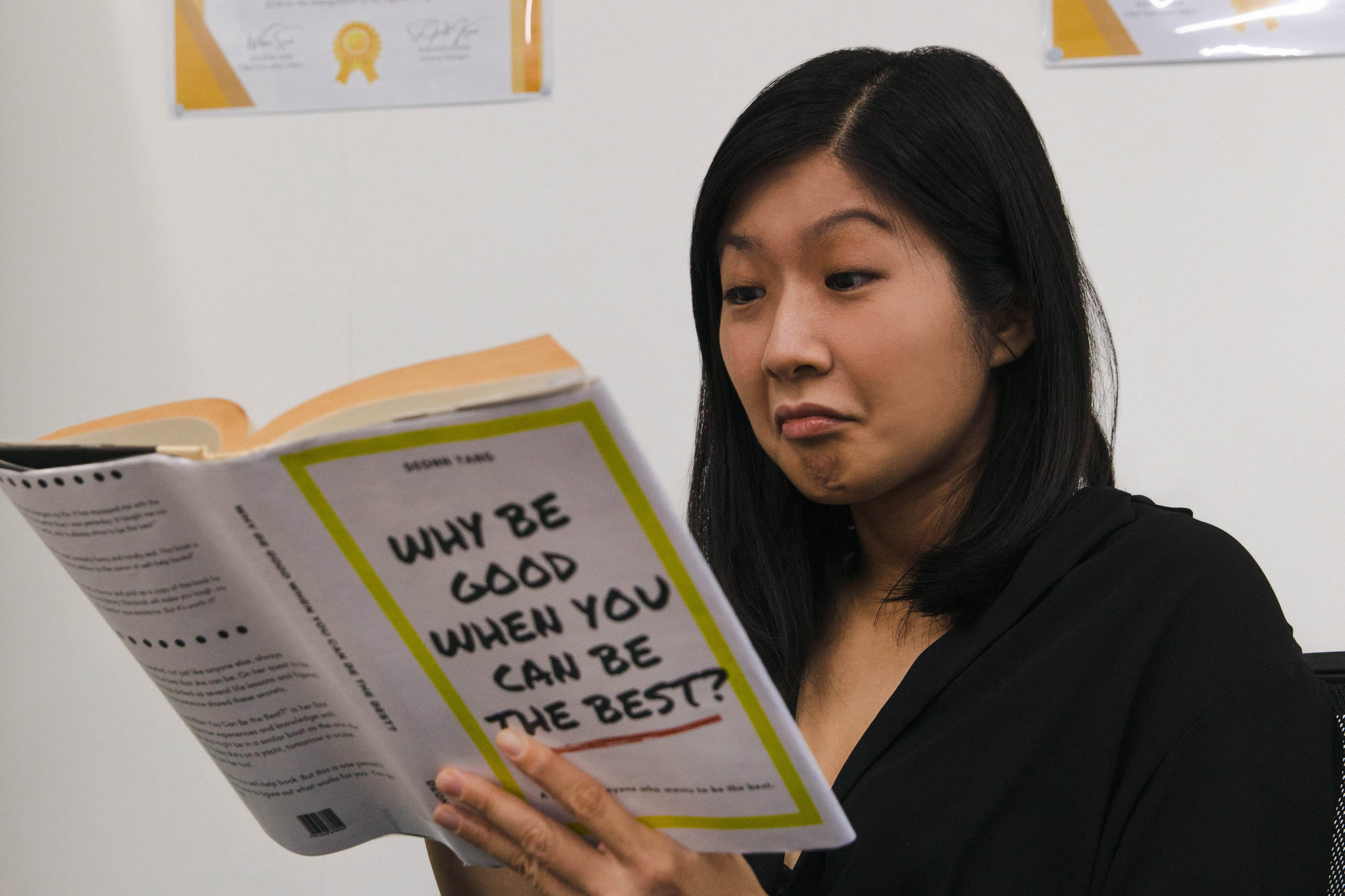 The same woman reading a book while looking impressed.