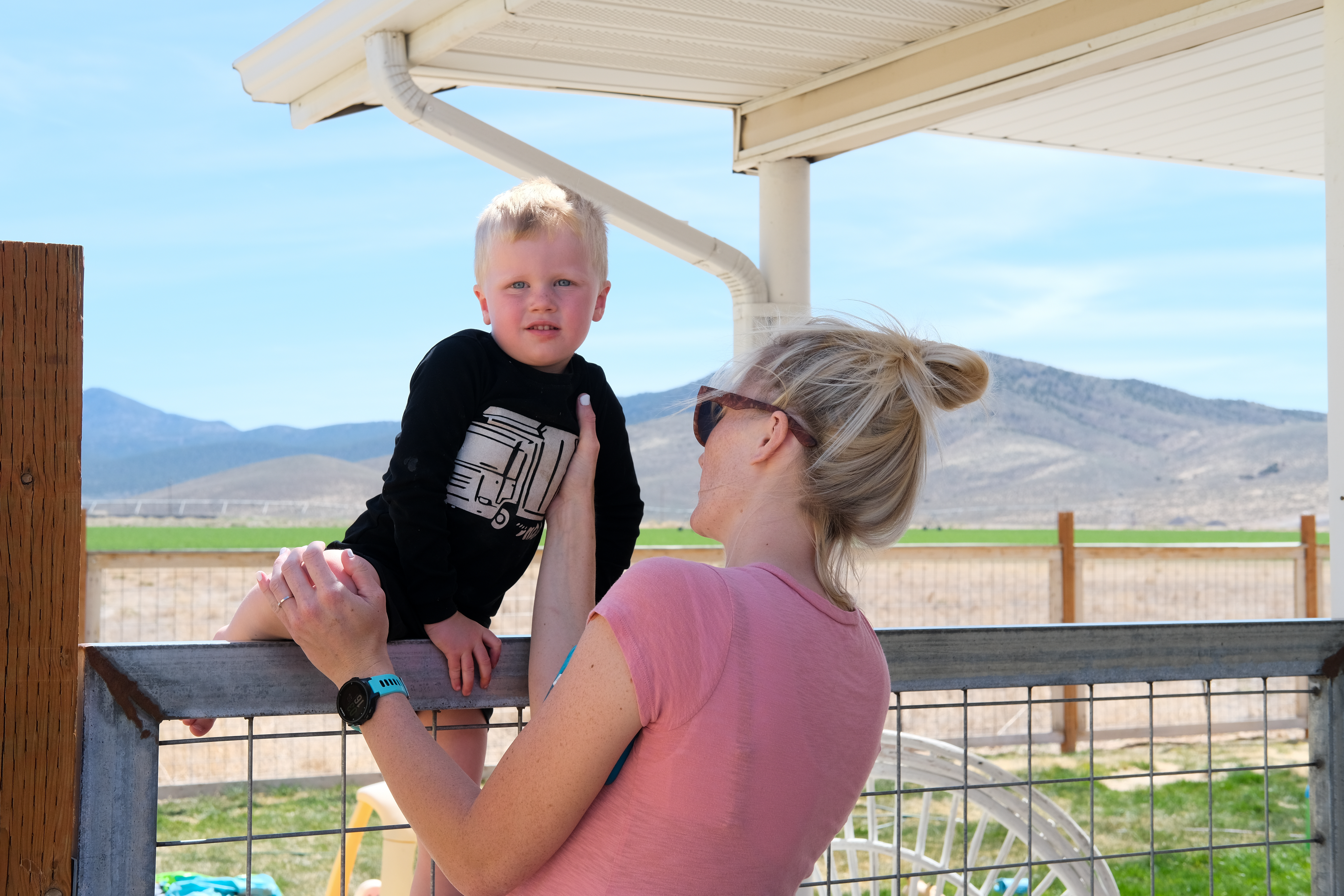 Baileigh helps her three-year-old son climb their fence in Circleville, UT.