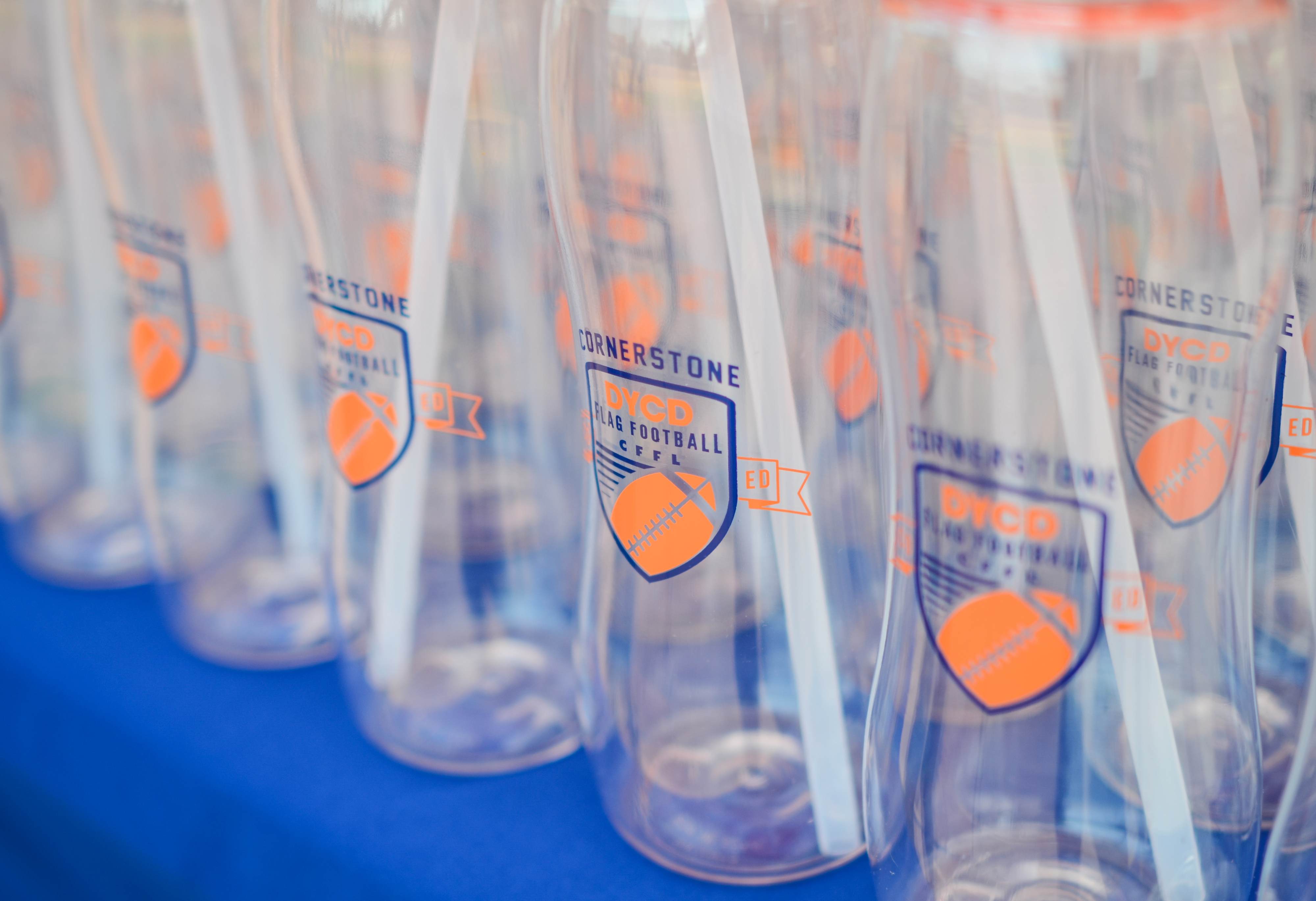 Clear water bottles displaying the Cornerstone DYCD Flag Football two color blue and orange logo.