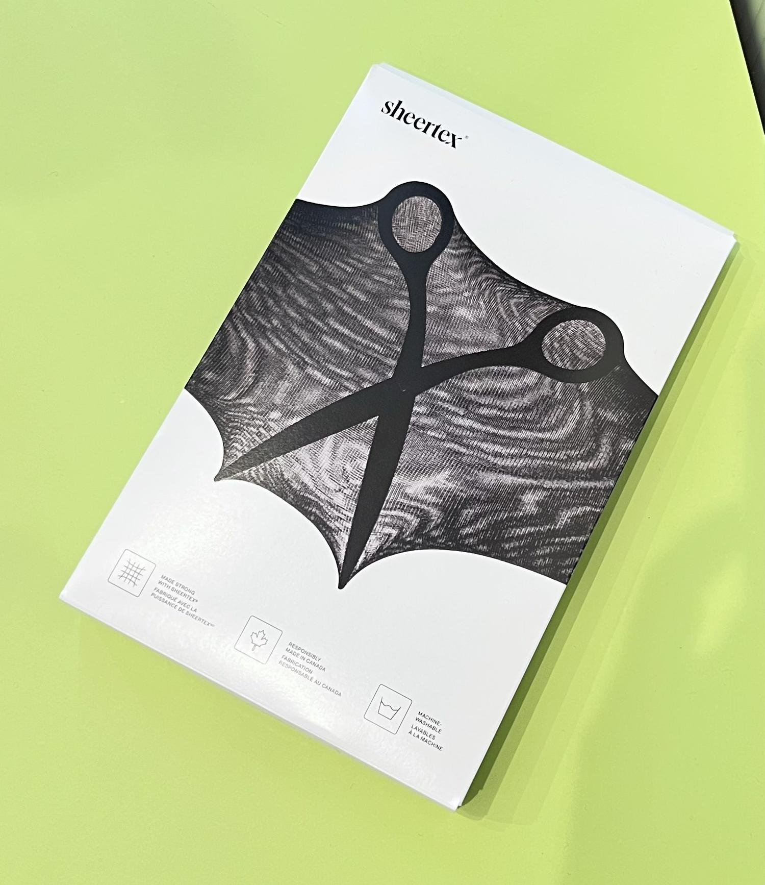 Close-up of Sheertex tights packaging with scissors graphic on lime green background.