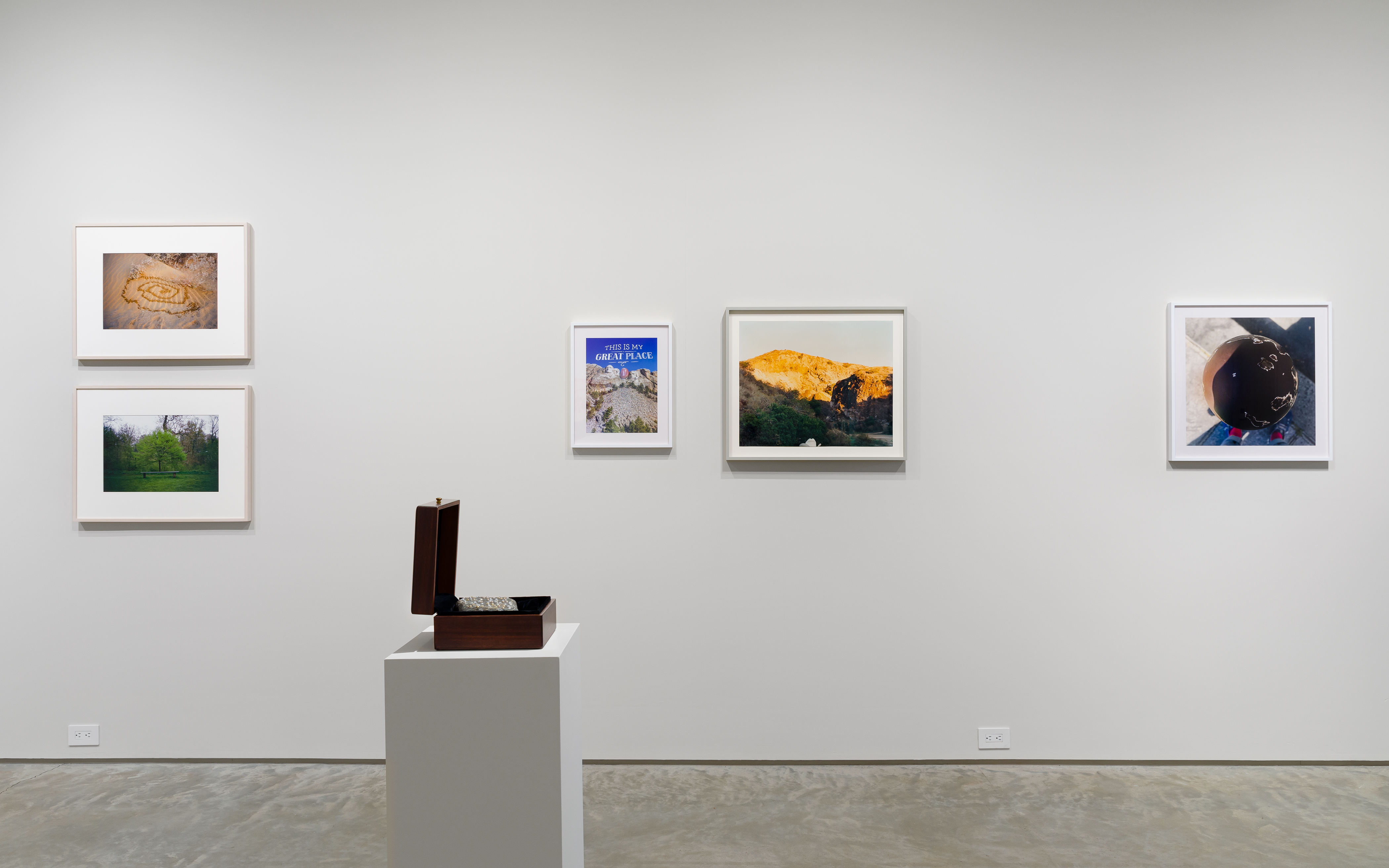 From left: Gabriel Orozco, "Spiral Pee Pee," 2005, C-print, 16 x 20 inches. Gabriel Orozco, "Tree Bench," 1996, C-print, 12 7/8 x 18 5/8 inches. Nina Katchadourian, "Extra Large Barnacled Rock," 2002, Rock with barnacles and googly eyes in wood box, unique. Rock: 7 x 5 inches, Box: 8 1/4 x 7 3/4 x 4 1/4 inches. Nina Katchadourian, "This is My Great Place," 2015 ("Seat Assignment" project, 2010 and ongoing), C-print, Edition of 8 + 2AP; edition X/8, 19 x 15 1/4 inches. Jonathan Monk, "The space above Bruce Nauman's head," 1997, C-print, 19 11/16 x 23 5/8 inches. Nina Katchadourian, "Globe 1," 2019, C-print, Edition of 8 + 2AP; Edition X/8, 24 x 24 inches. 