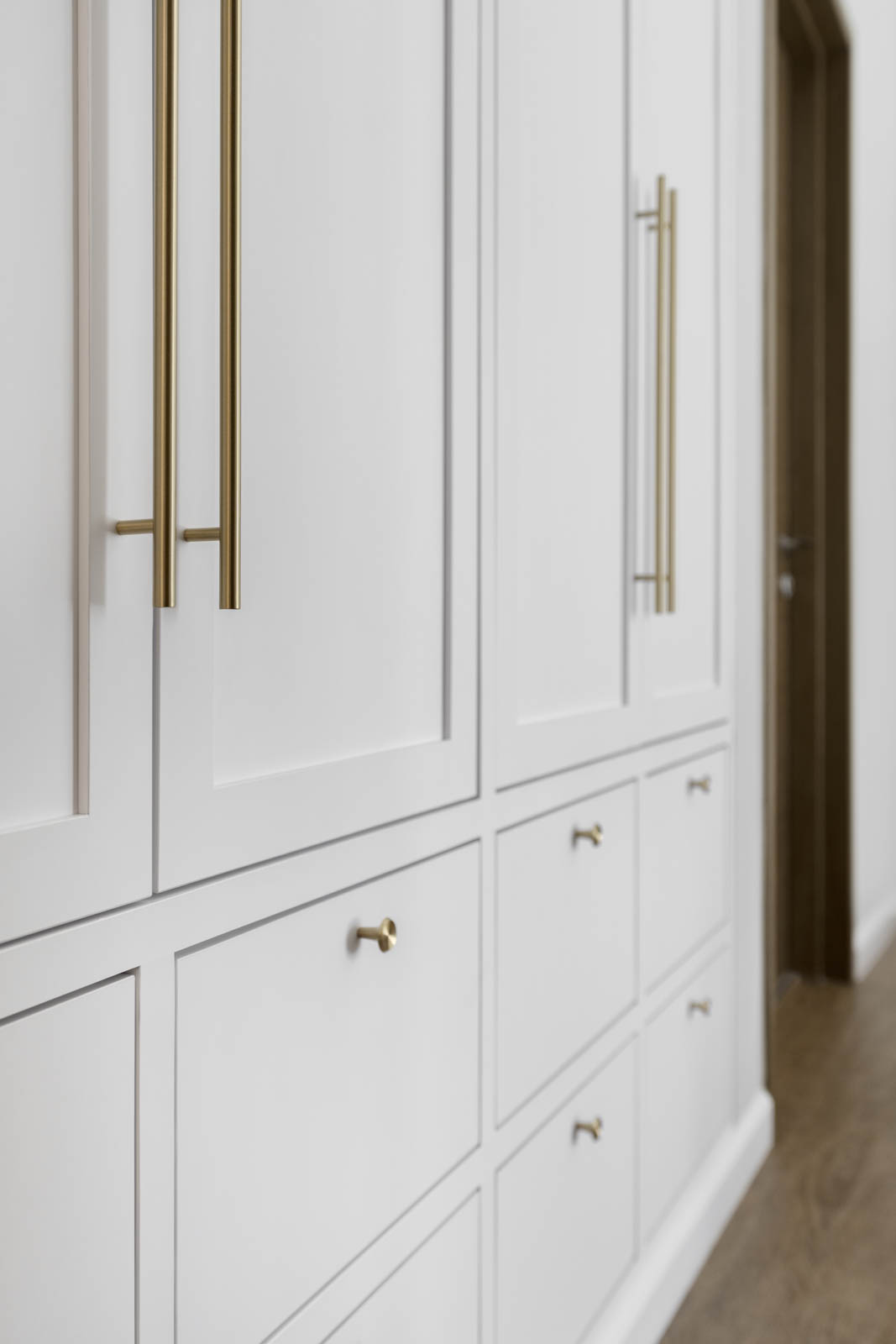 White shaker wardrobe plays a clean and refreshing look with the gold coated handles.