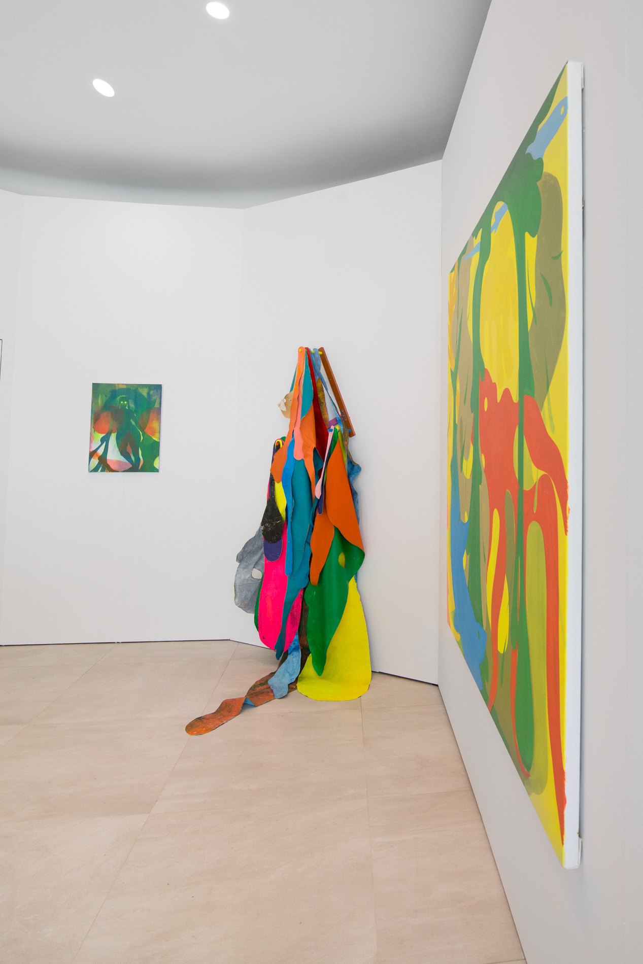 Nadir Sourgi, Installation view of Metonym at Bas Fisher Invitational as part of Waterproof Miami, Photo by Monica McGivern (2022). Displayed on the back wall of a white gallery is Splasher, to the right Hangover Painting #58 is displayed along the corner, with Carnival Shit Hands (yellow) on the adjacent right wall.