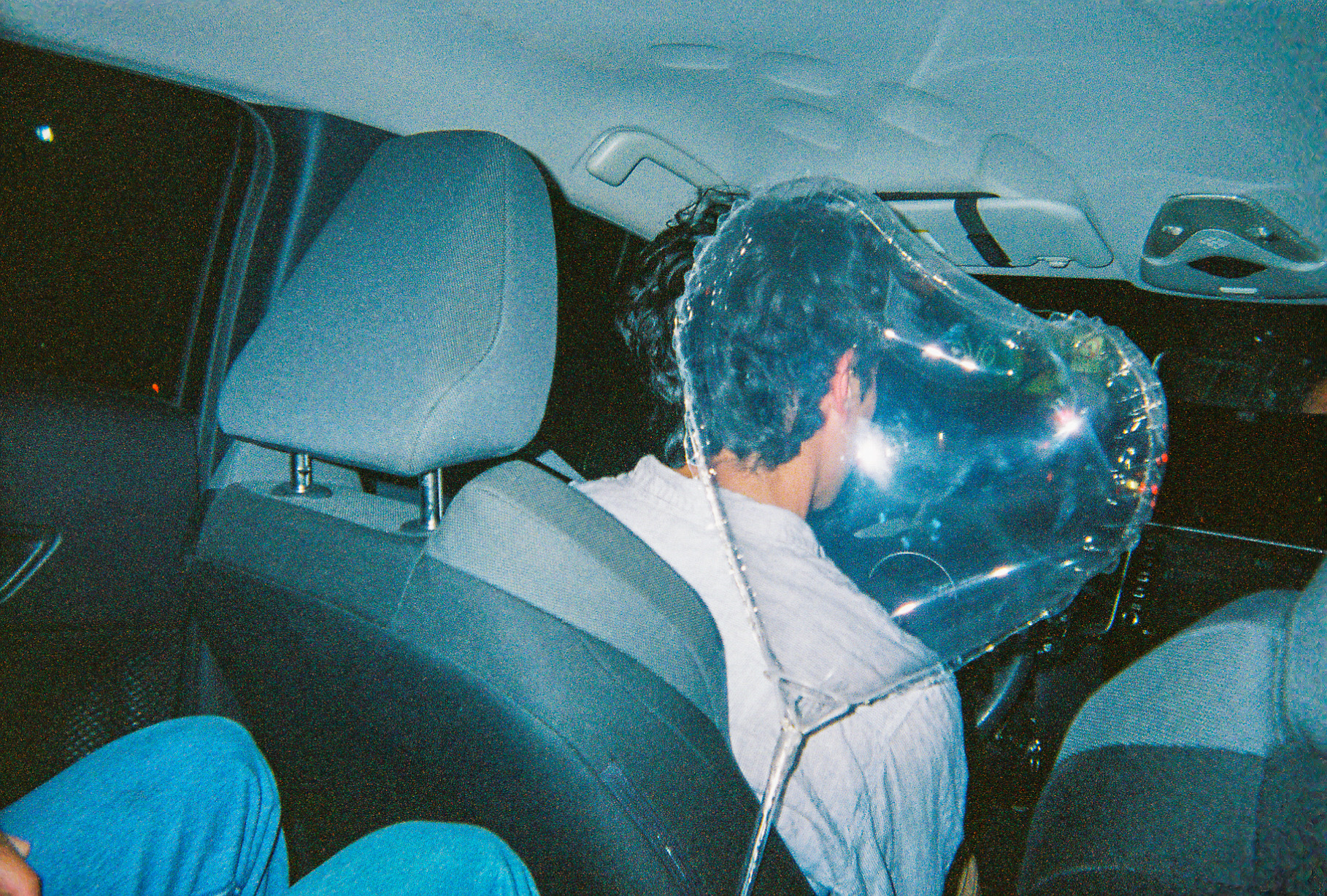 A man in a car with a heart balloon behind him