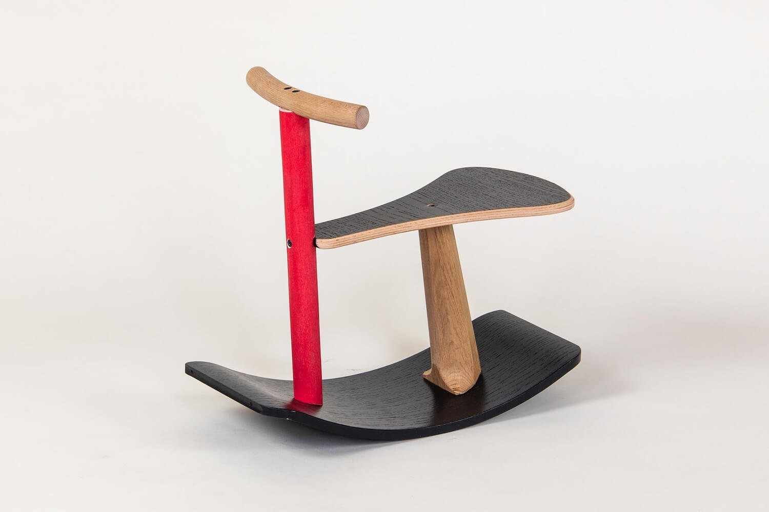 A black, plywood and red rocking stool