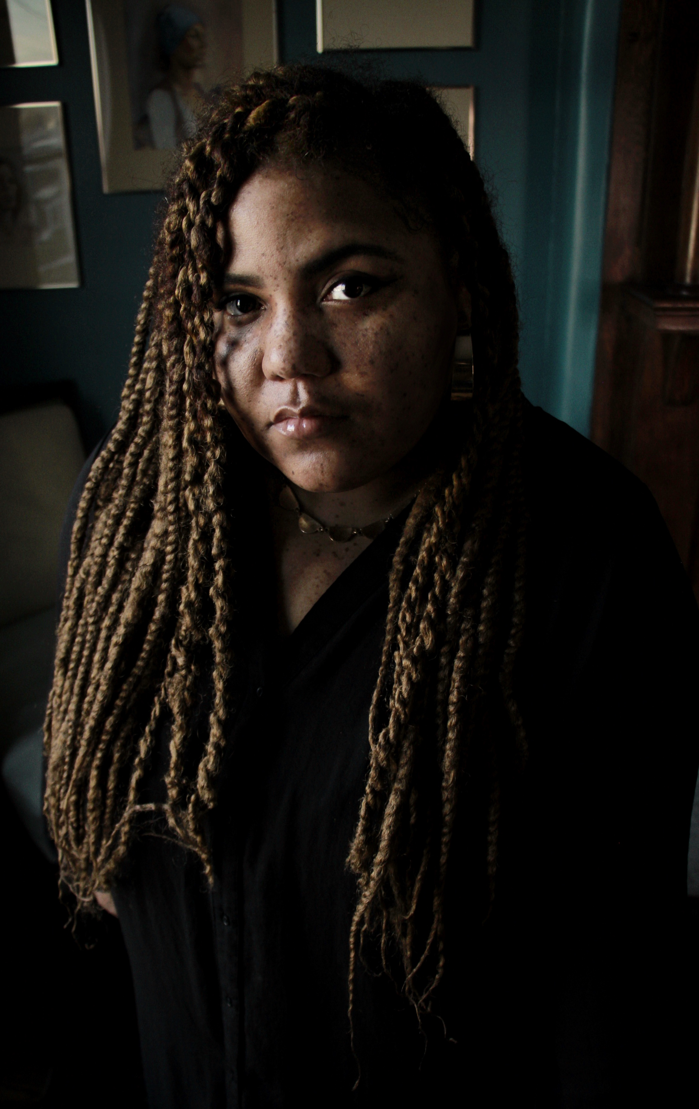 Portrait headshot of Ashley Cathey, who has long elbow-length hair, and whose head is tilted slightly to the left. Shadows cover a lot of the image.