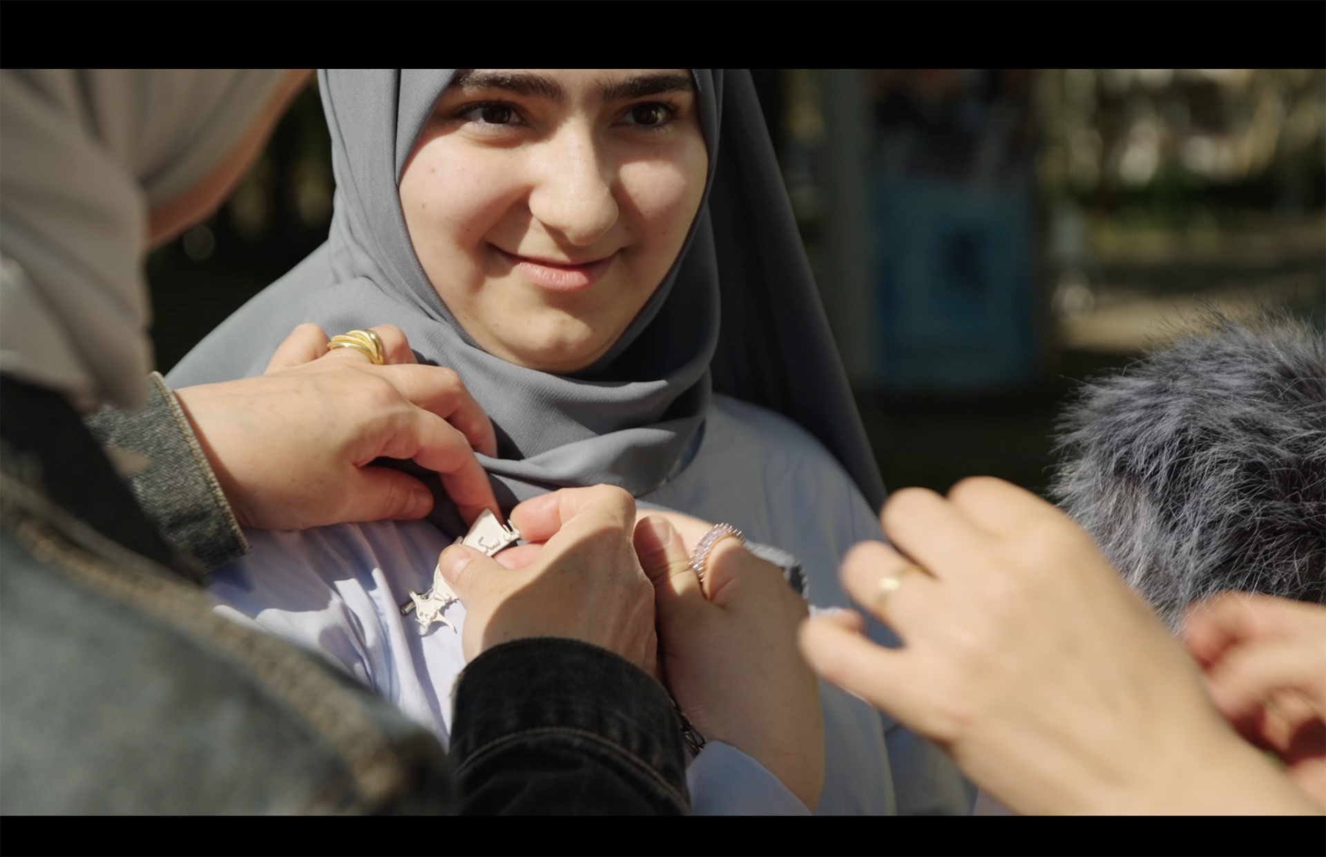 Video still. A memento is given to a passer-by Joudy. Parts of the monument are distributed throughout the neighborhood and the memory is shared with different people. Giesing, 2023. Image: Mathias Reitz Zausinger.