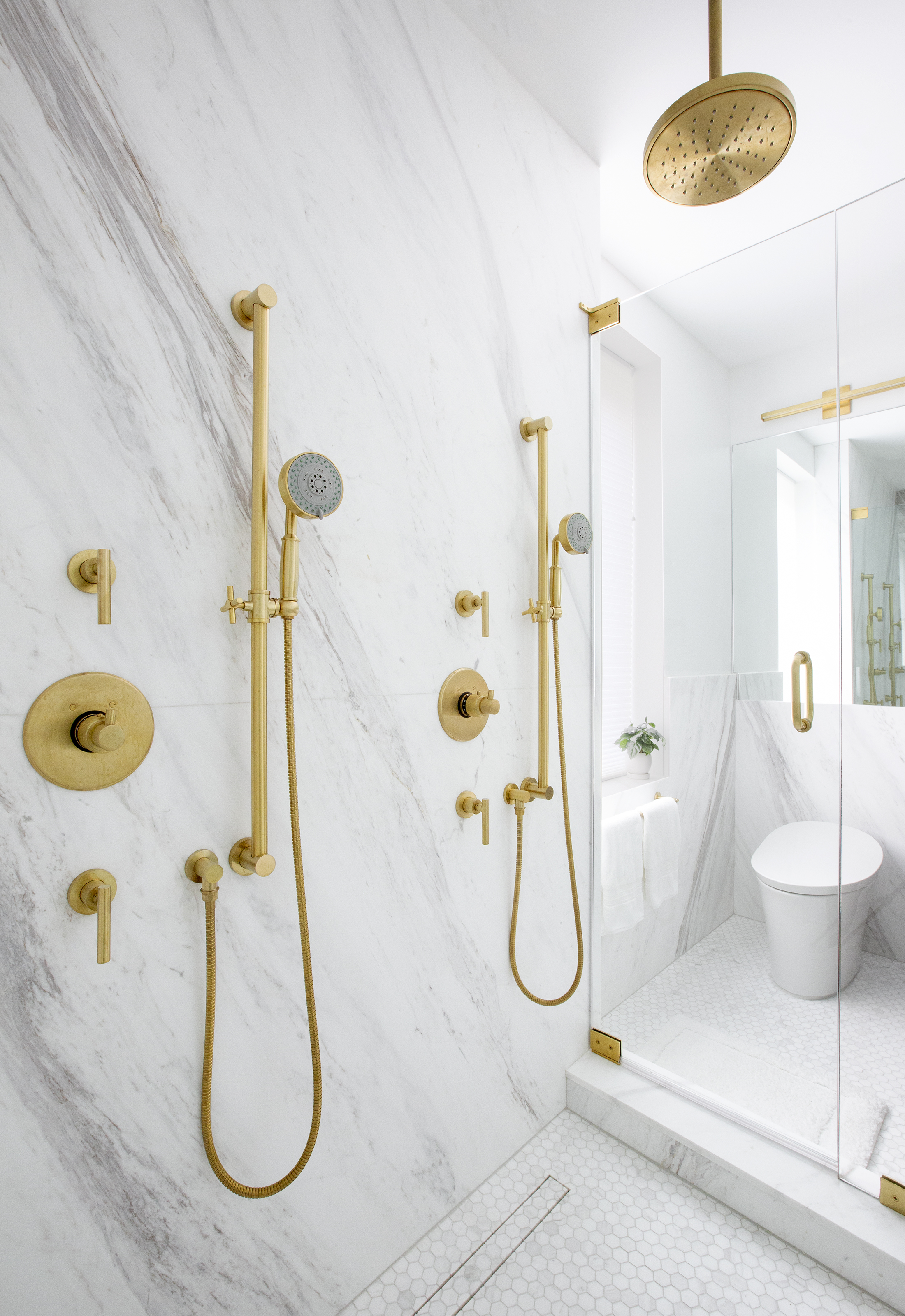 Luxurious modern bathroom in a high-end New York City apartment, featuring elegant gold fixtures and a marble shower, designed by a Brooklyn-based residential architect specializing in townhouse renovations and contemporary interiors
