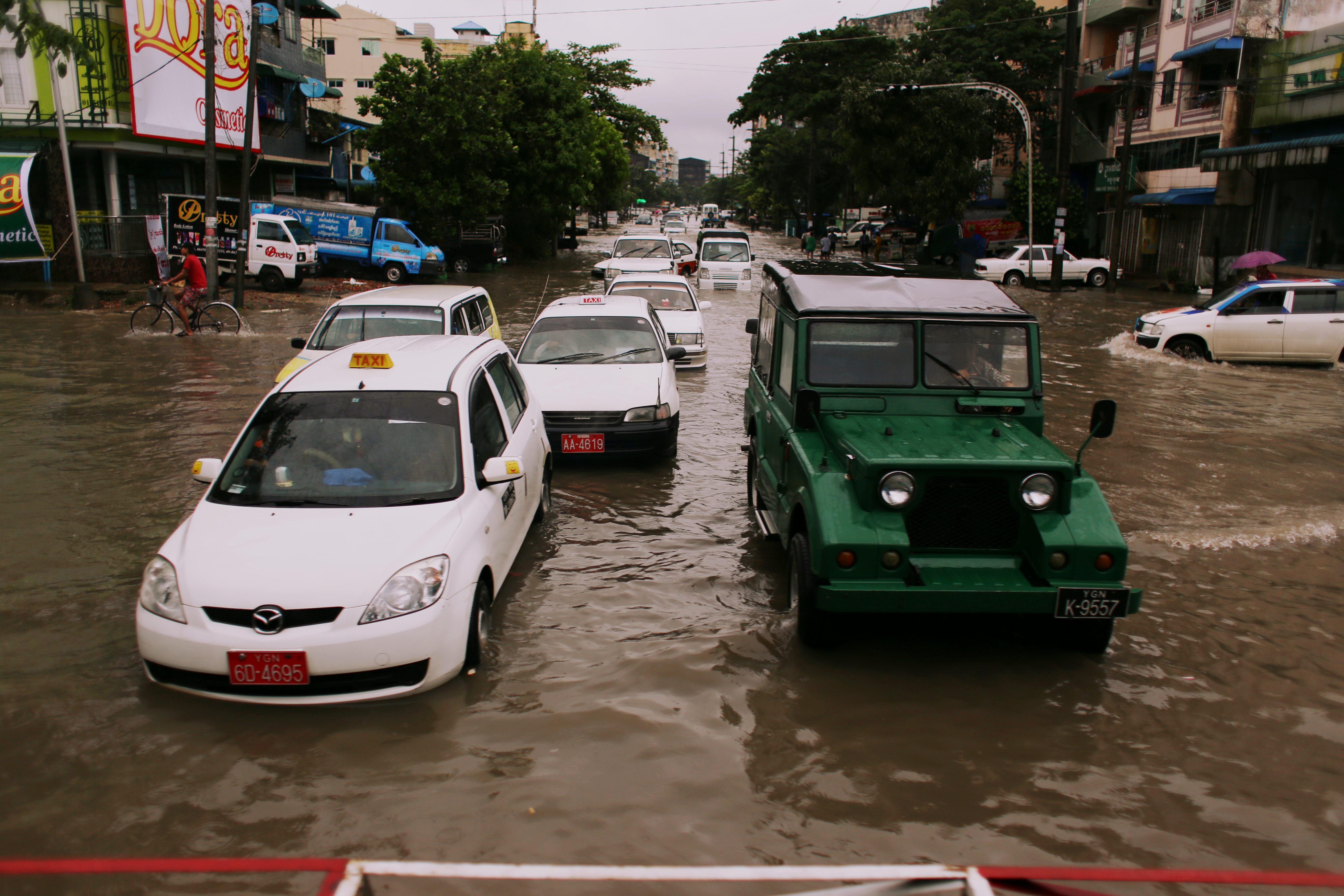 Heavy rainfall over the past few days has flooded many of the roads, like this one at a level crossing near Ngamoeyeik Creek. Passengers take off their shoes and wade precariously through the knee-deep water to reach the train.