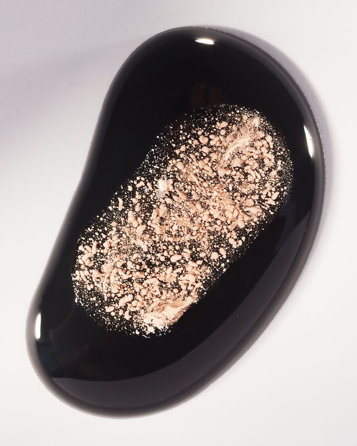 KMA photographer Vincent Gapaillard photographs powdery pink blush spilled into black nail polish on a white surface 