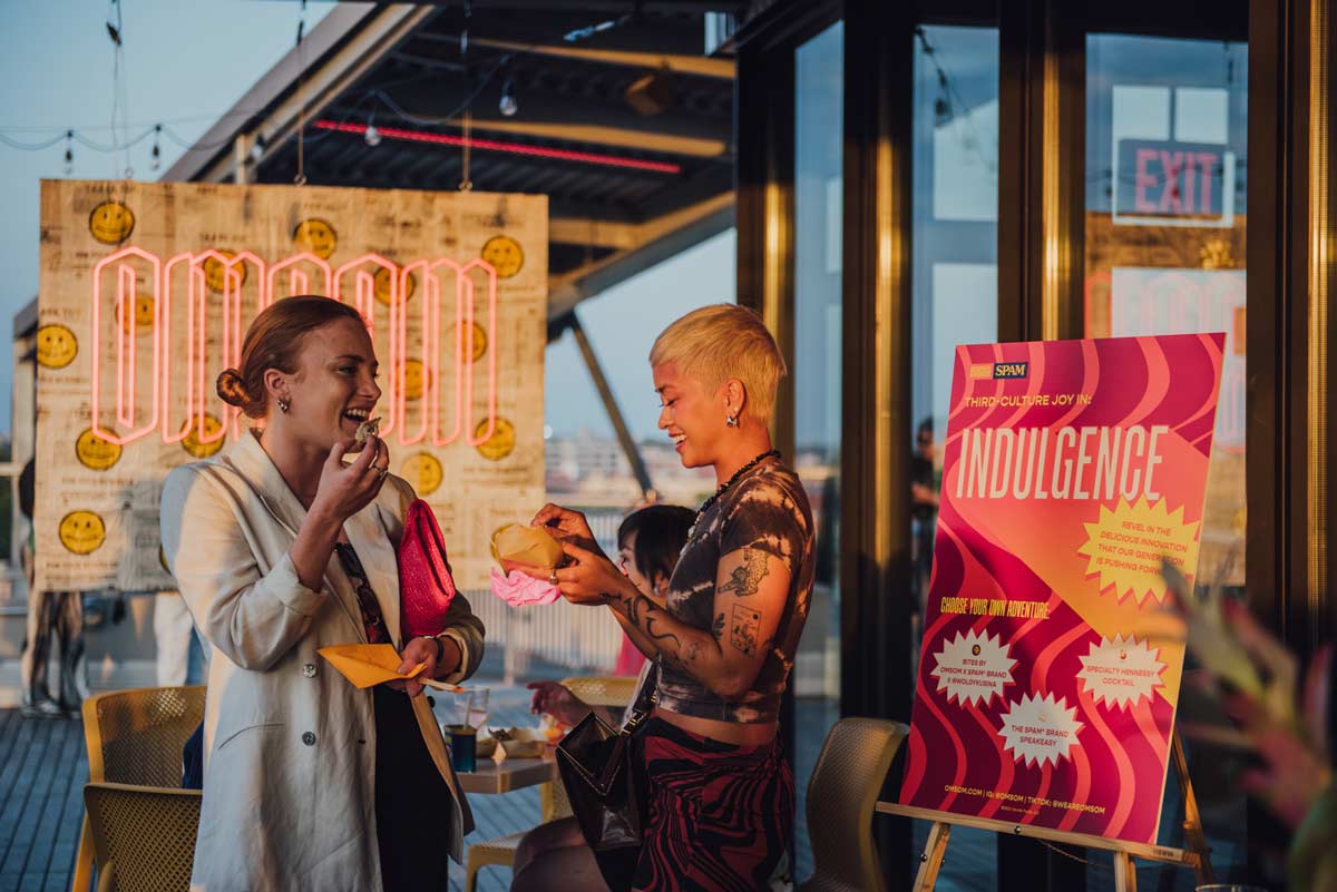 2 people enjoying their food in front of Omsom poster