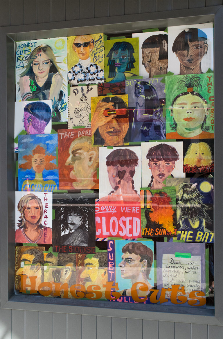 A photo of the front left window of The New Gallery's storefront, in the window are all of the paintings from the "Honest Cuts" project hung in a collage. 