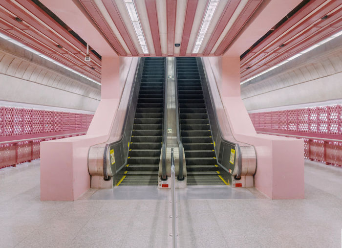 Pink metro station in Singapore with the focal point being to gray escalators.