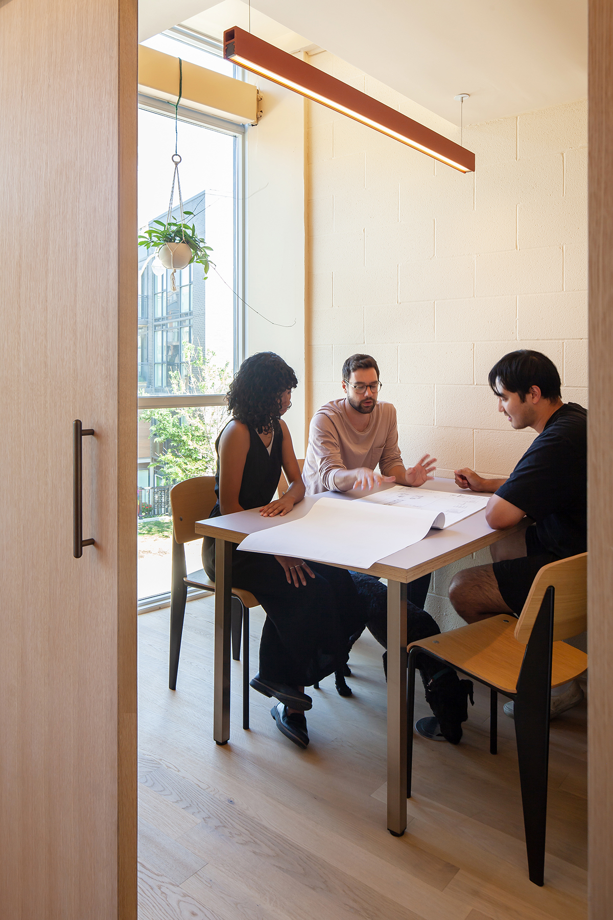 Interior photo of team members in small meeting room with terracotta light fixture
