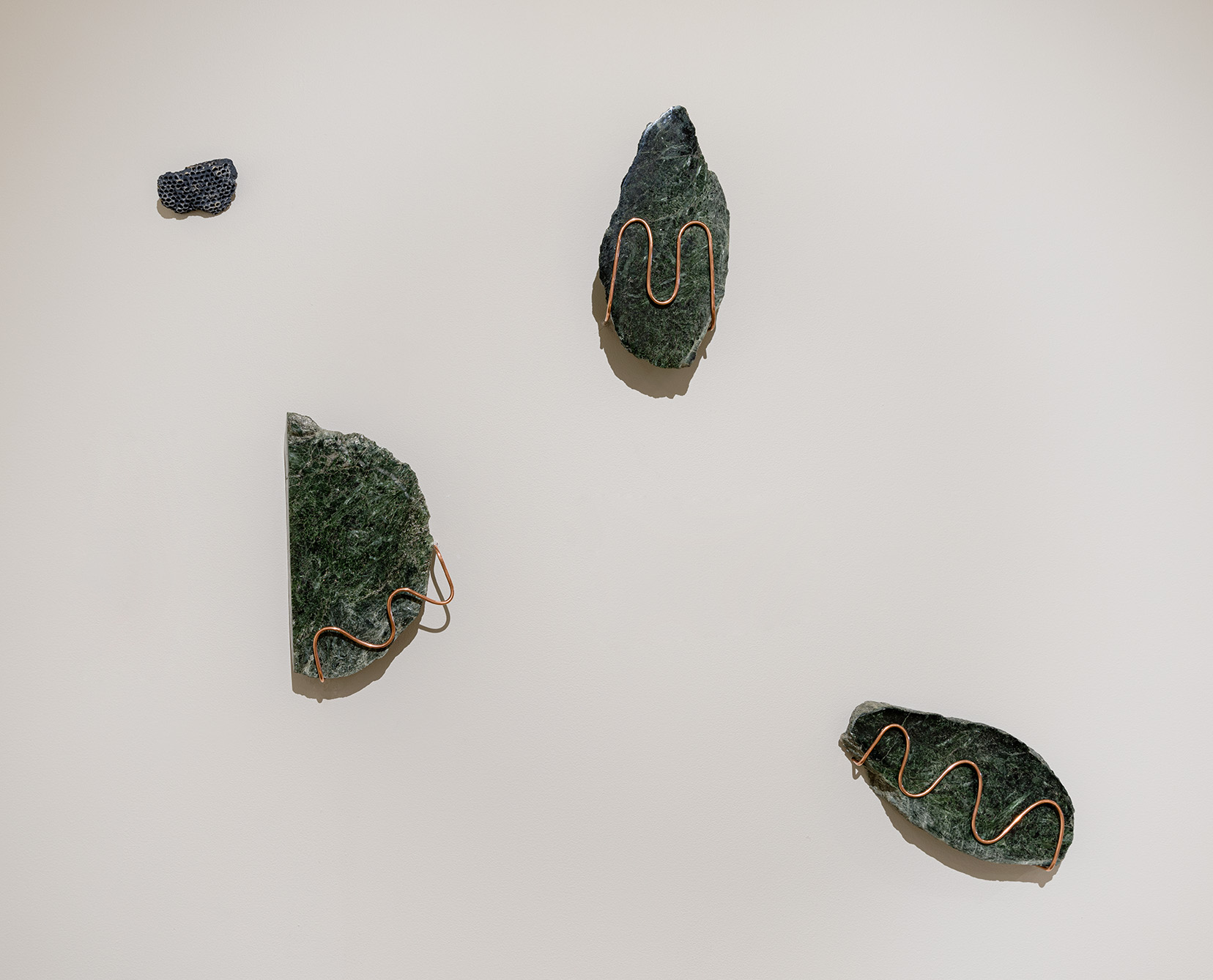(From left to right) Joel Kuennen, "Living Earth IV," 2023. Serpentinized olivine (California), copper, beeswax, 10 x 8 x 3 inches; "Living Earth I," 2023. Serpentinized olivine (California), copper, beeswax, 10 x 6 x 3 inches; "Living Earth III," 2023. Serpentinized olivine (California), copper, beeswax, 5 x 10 x 2 inches. Photo by Etienne Frossard. 