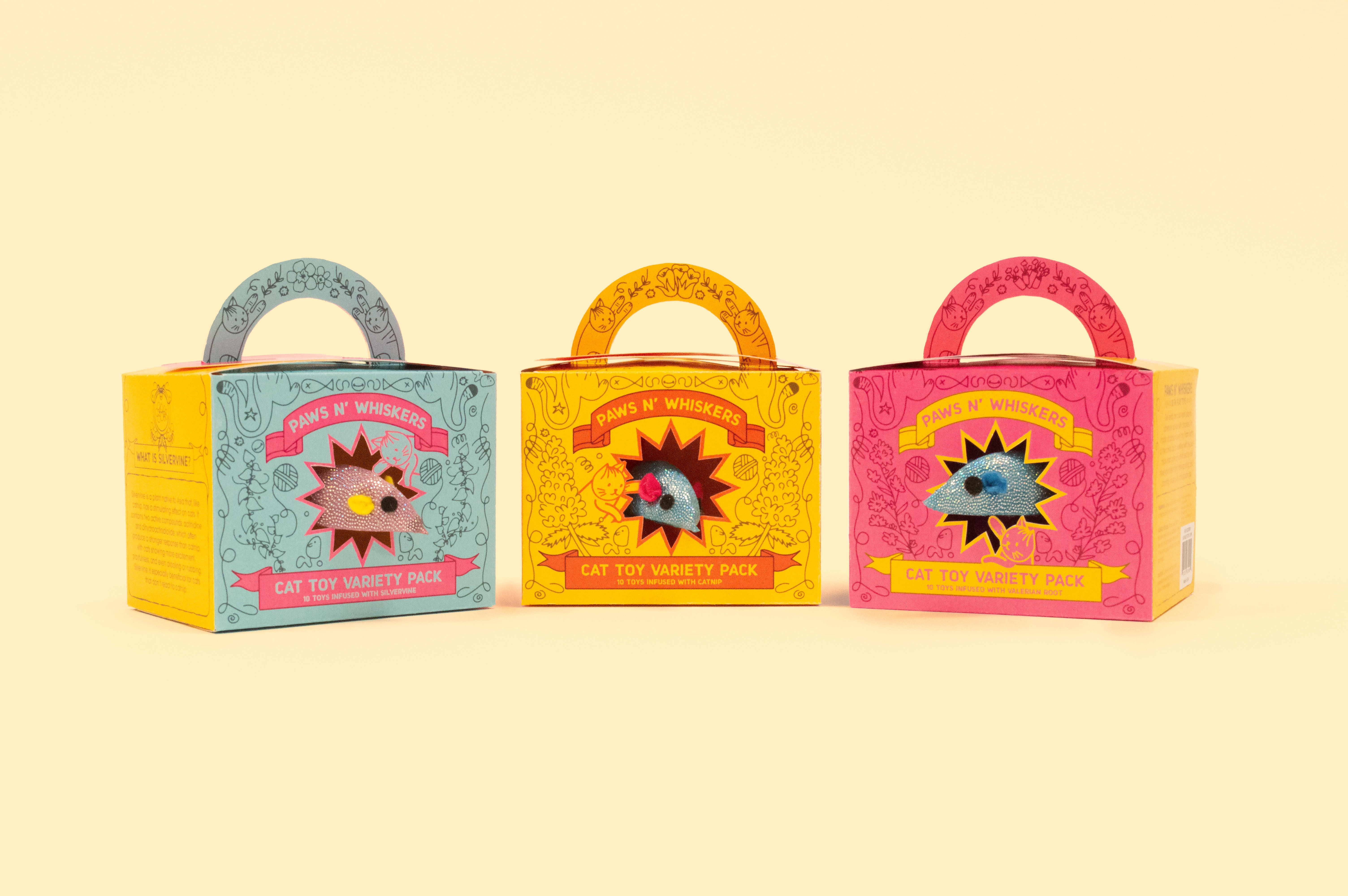 A light yellow studio shot showcase a front view of all three cat toy packages.