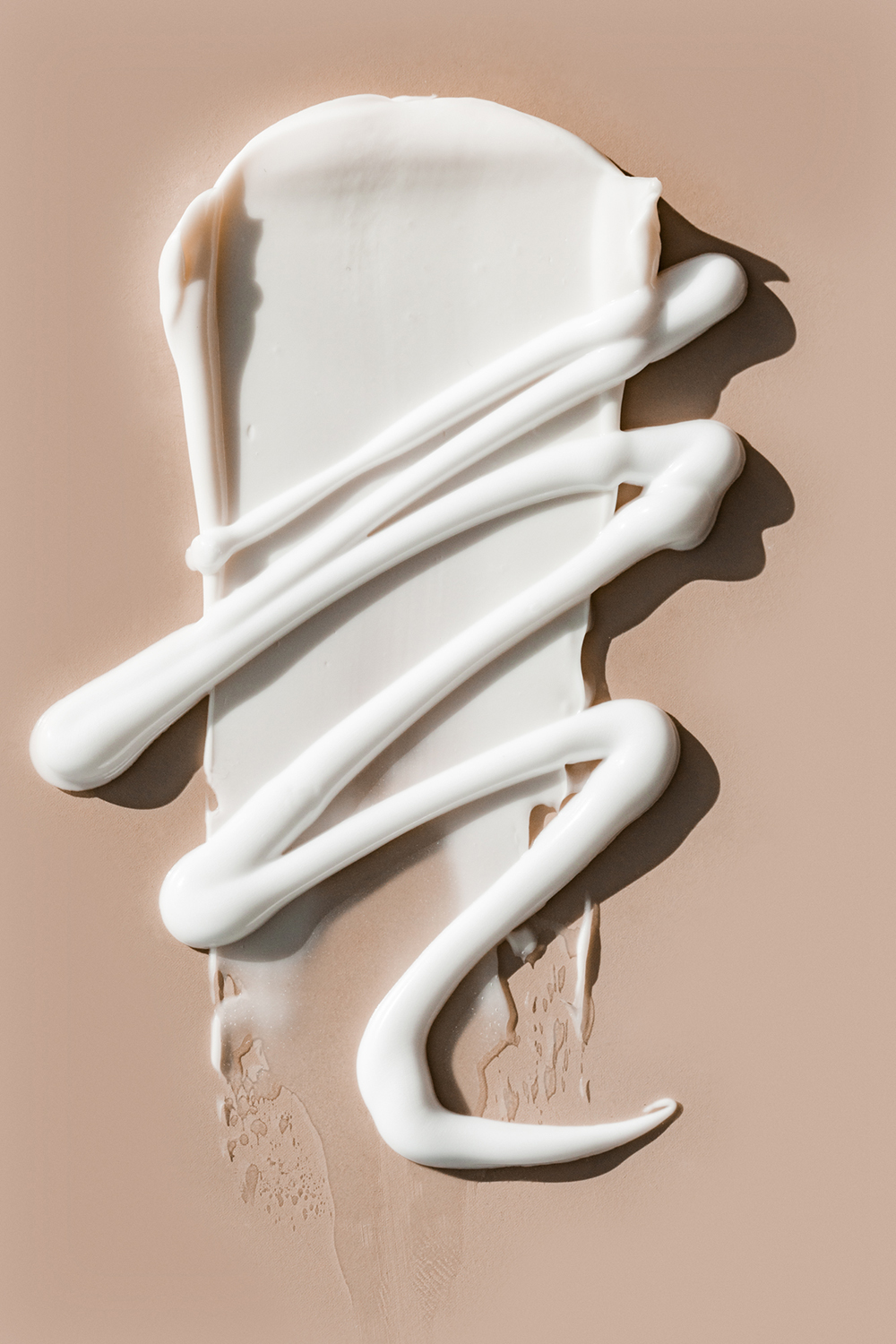 KMA stylist Sara Wacksman designs set for texture photo of creamy white moisturizer smeared on tan background for Glossier