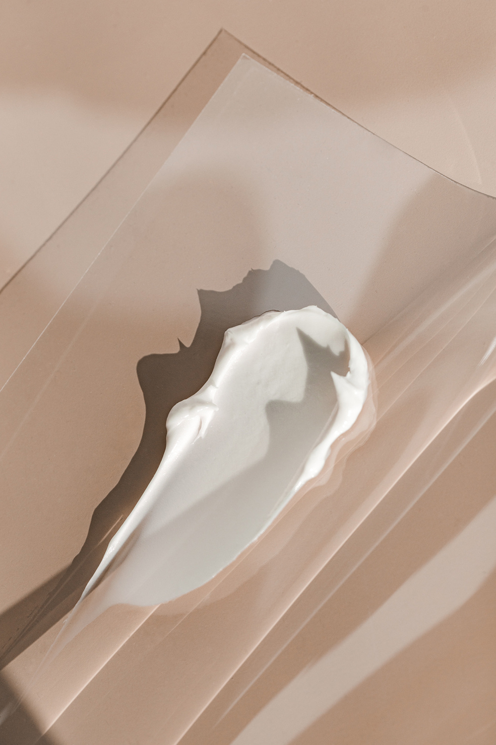 KMA stylist Sara Wacksman designs set for texture photo of creamy white moisturizer smeared on tan background for Glossier
