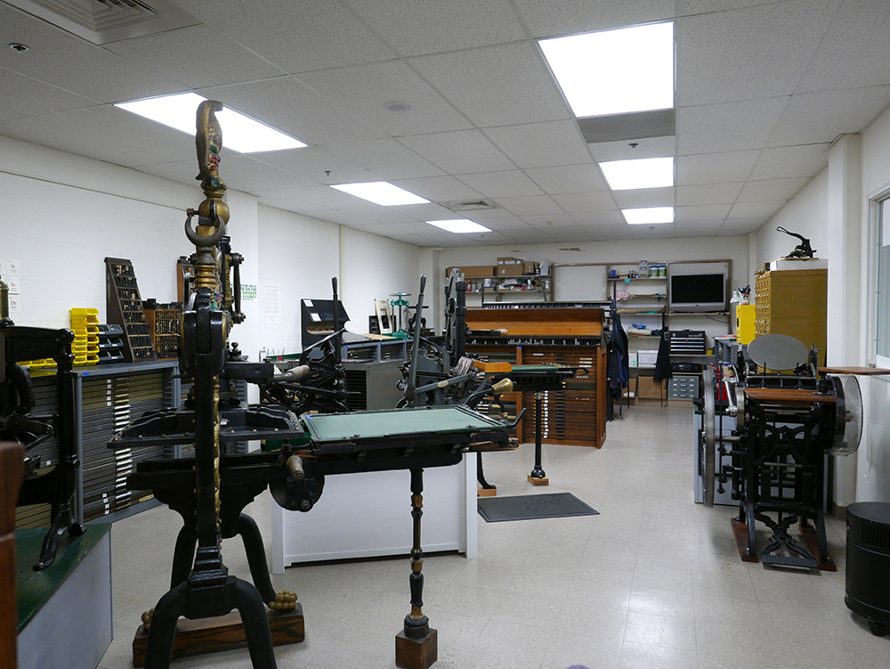 View of a hand-press printing workshop. Several different hand-presses and type cabinets are installed throughout the space.