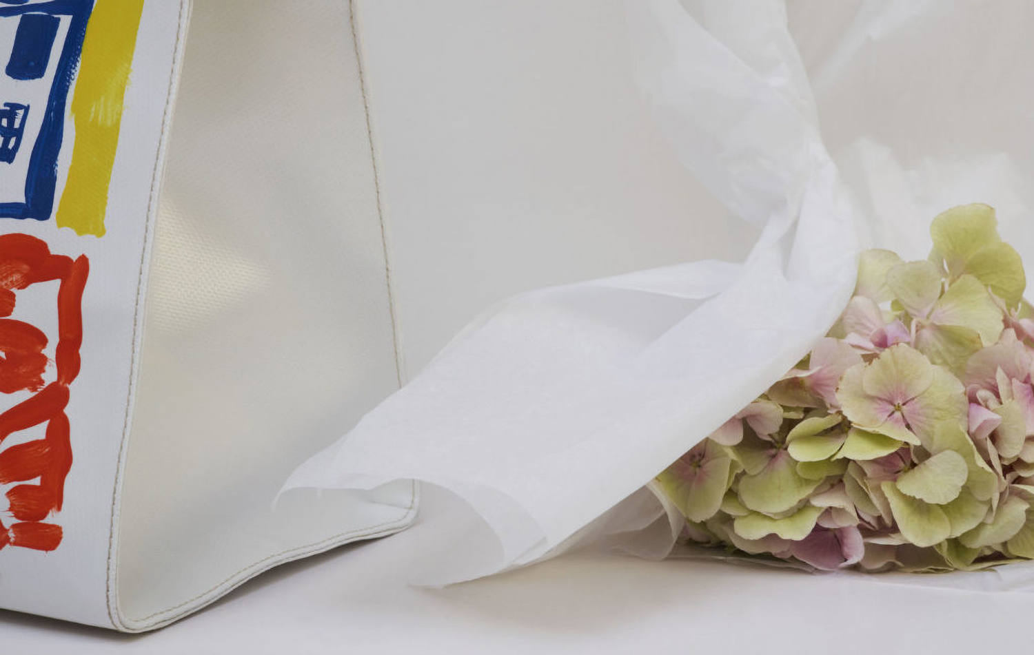 KMA photographer Daniel Schweizer shoots a white piece of paper and a pink flower on a white surface