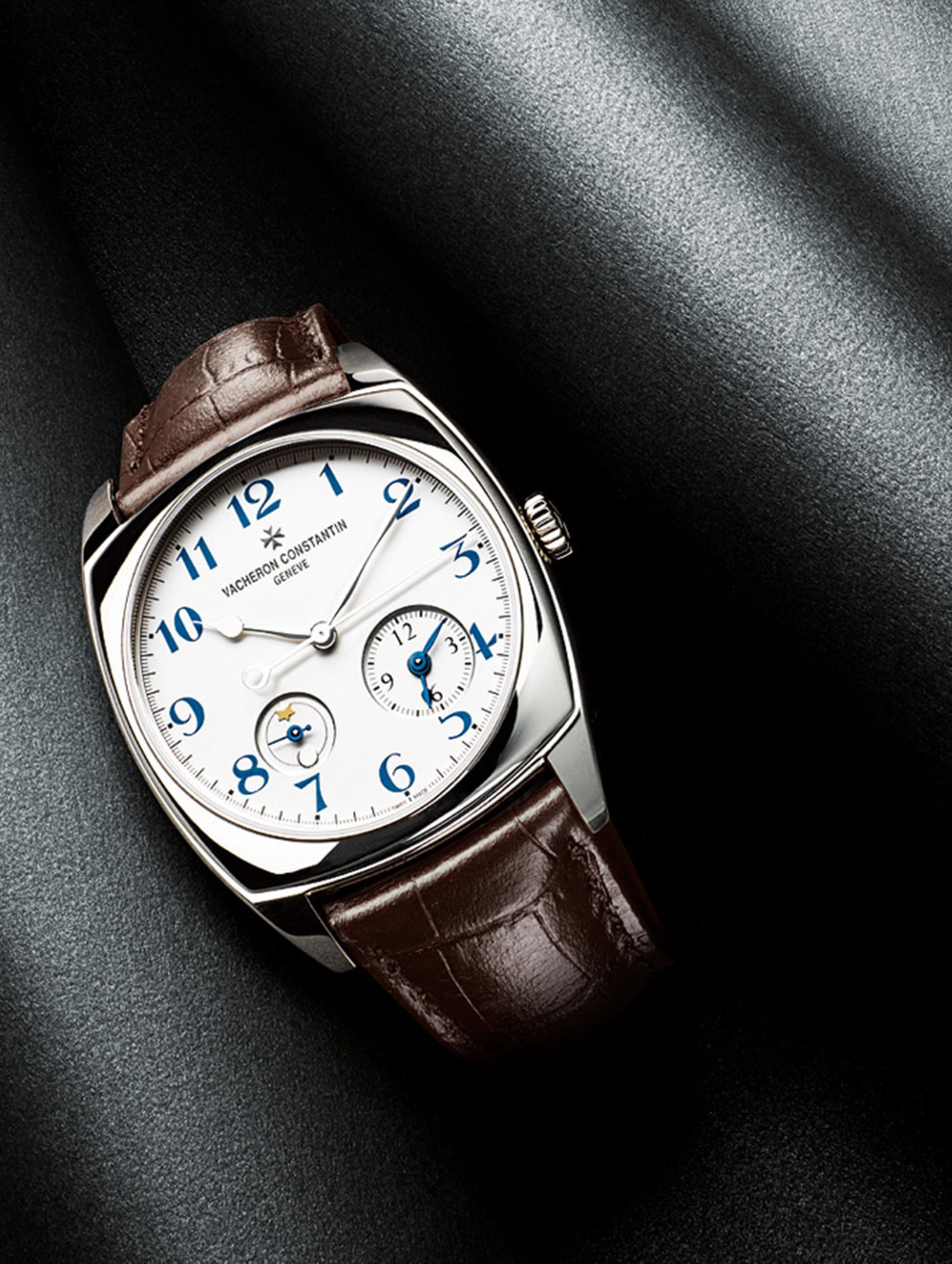 KMA stylist Sara Wacksman designs set for a photo of a watch with a brown leather strap resting on a shiny grey surface 