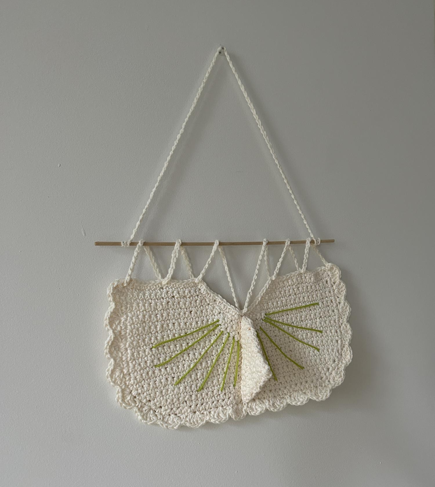 A sundial woven from yarn, hanging on a wall