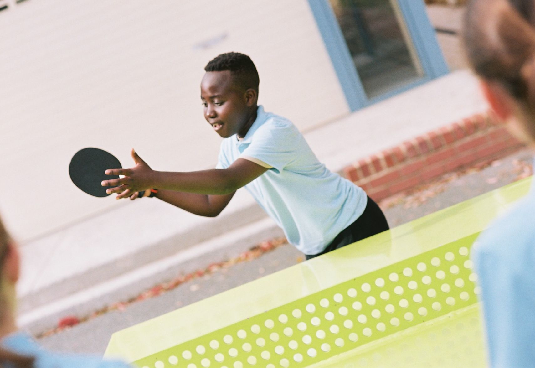 a primary school student playing ping pong on a POPP outdoor table tennis table