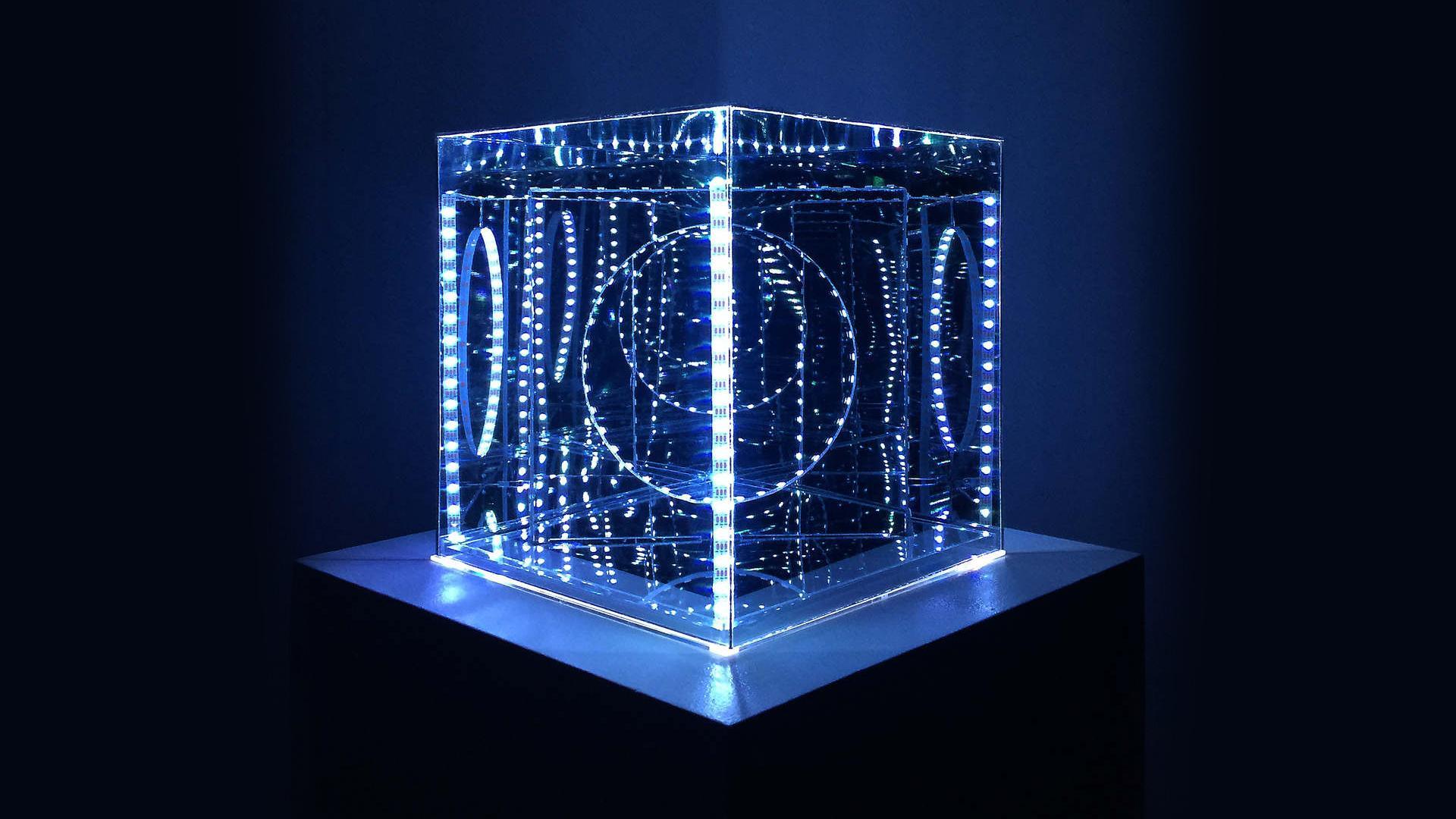A clear box with blue lights and circles cut into it in a dark room.