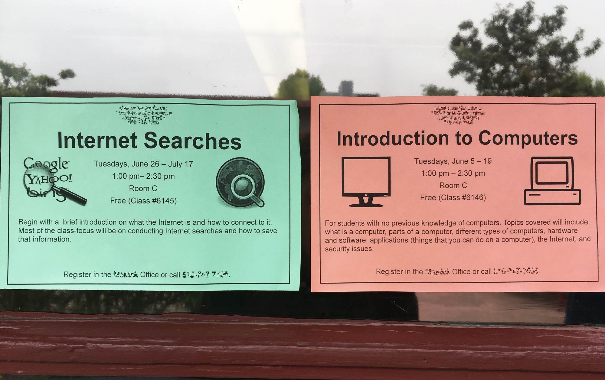 Two flyers on a window; one reads 'Internet Searches' and the other reads 'Introduction to Computers'
