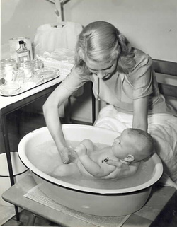 Leen, Nina, and Pix Publishing Inc. Mother Bathing Baby. Photograph. 1950s. Medical Center Archives of NewYork-PresbyterianWeill Cornell. 