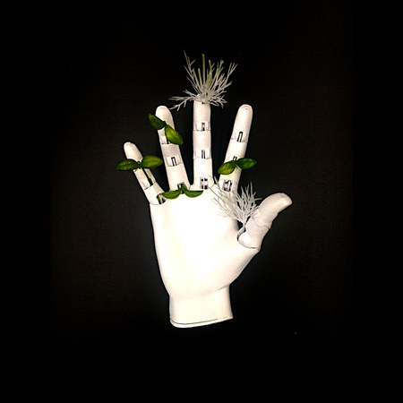 Picture of a robotic hand in open palm with plants growing out of finger joints.