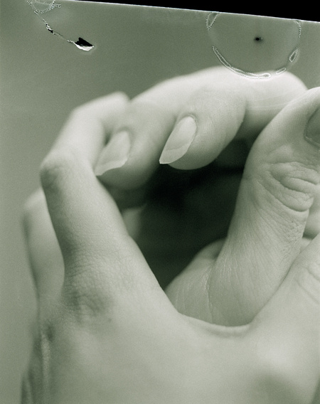 Fine art photograph of two hands holding each other, with puncture marks and tear, shot by UK-based photographer Ilayda Akarca