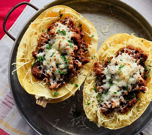 Two spaghetti squash still cooking on a pan