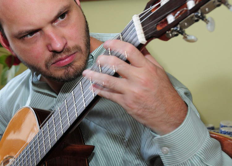 A headshot of a man holding or playing the guitar.