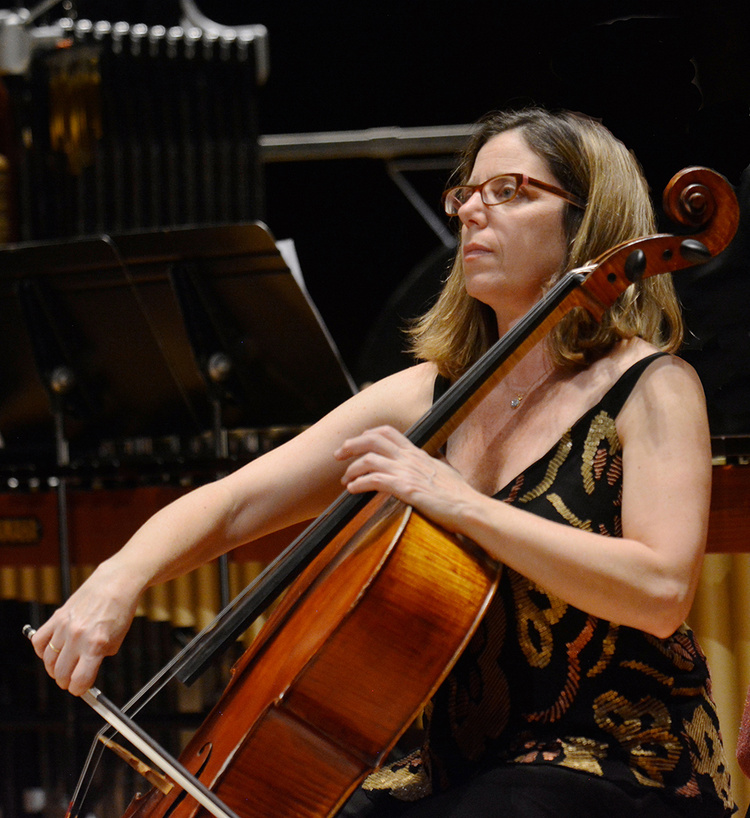 A half body shot of Maggie Parkins playing the cello.