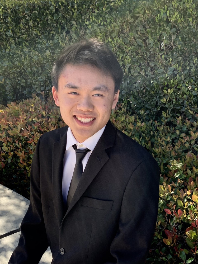 A headshot of pianist Justin Lee outdoors and against the bush.