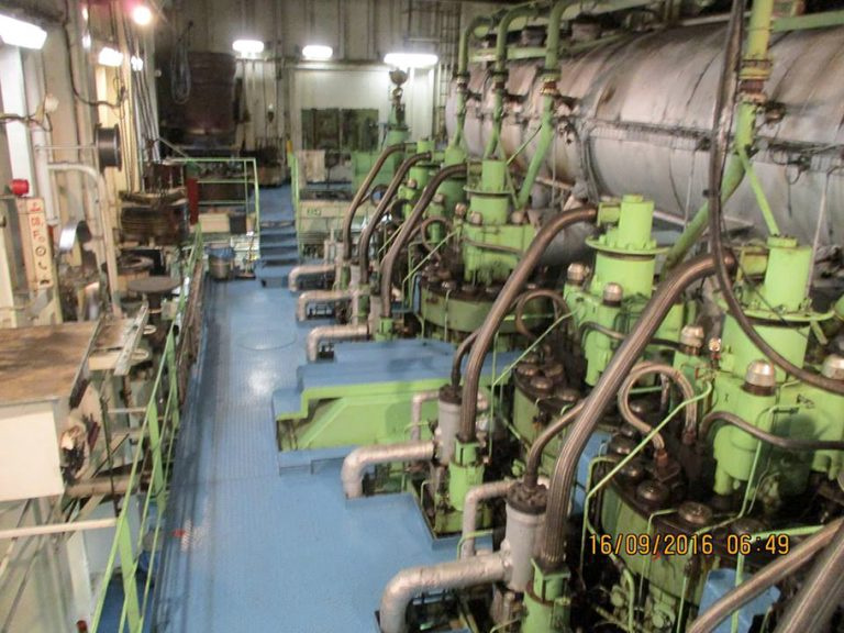 A blurry photo of inside the Atlantic Conveyor. It is a photo of the engine room, there are many metal pipes and several large green machines. On the right is a green metal fence which has several smaller machines behind it. The time stamp reads: "16/09/2016 06:49"